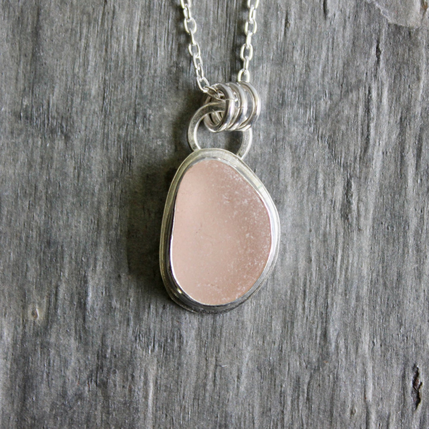 Necklace with a pink sea glass on a wooden surface