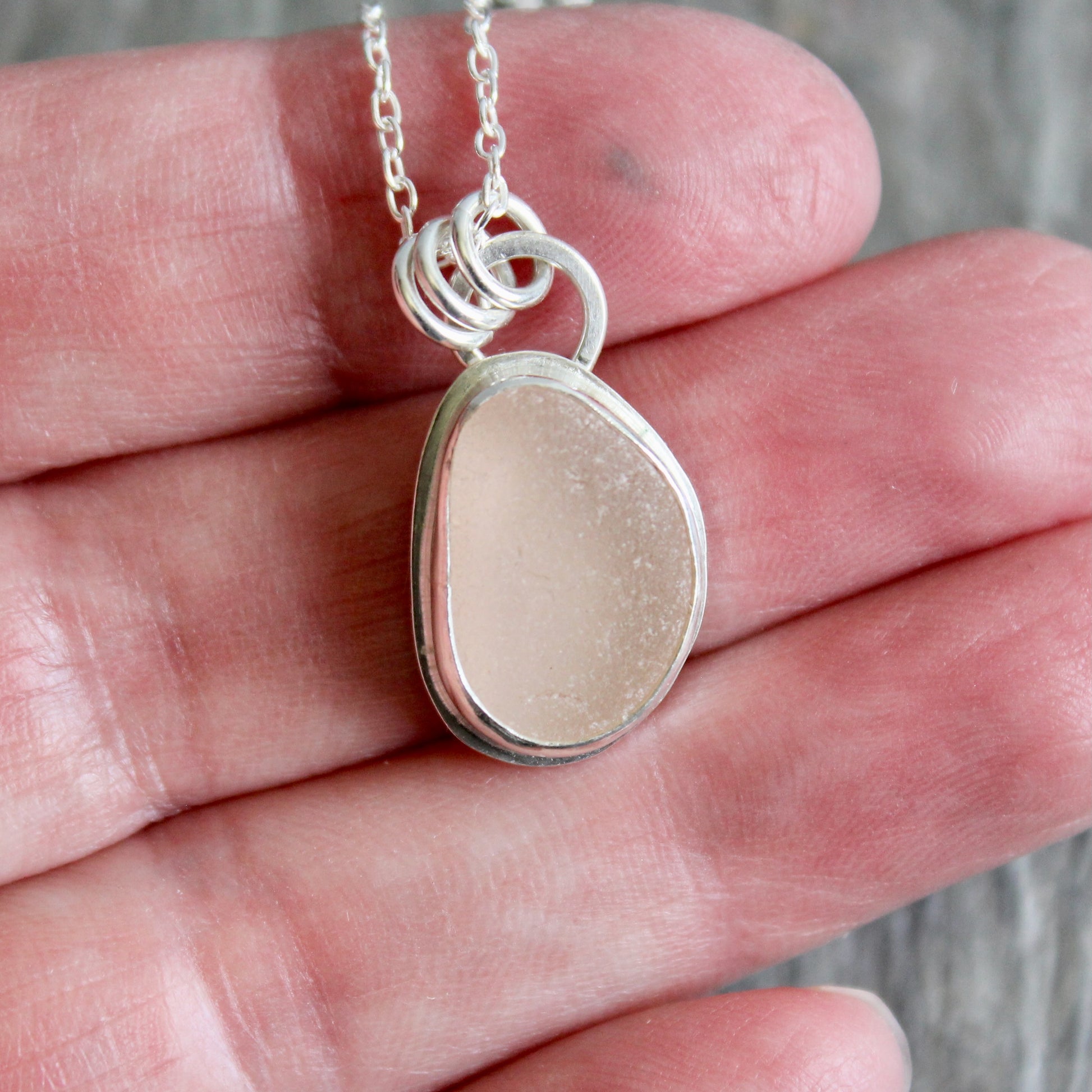 Silver necklace with a pink sea glass on a hand