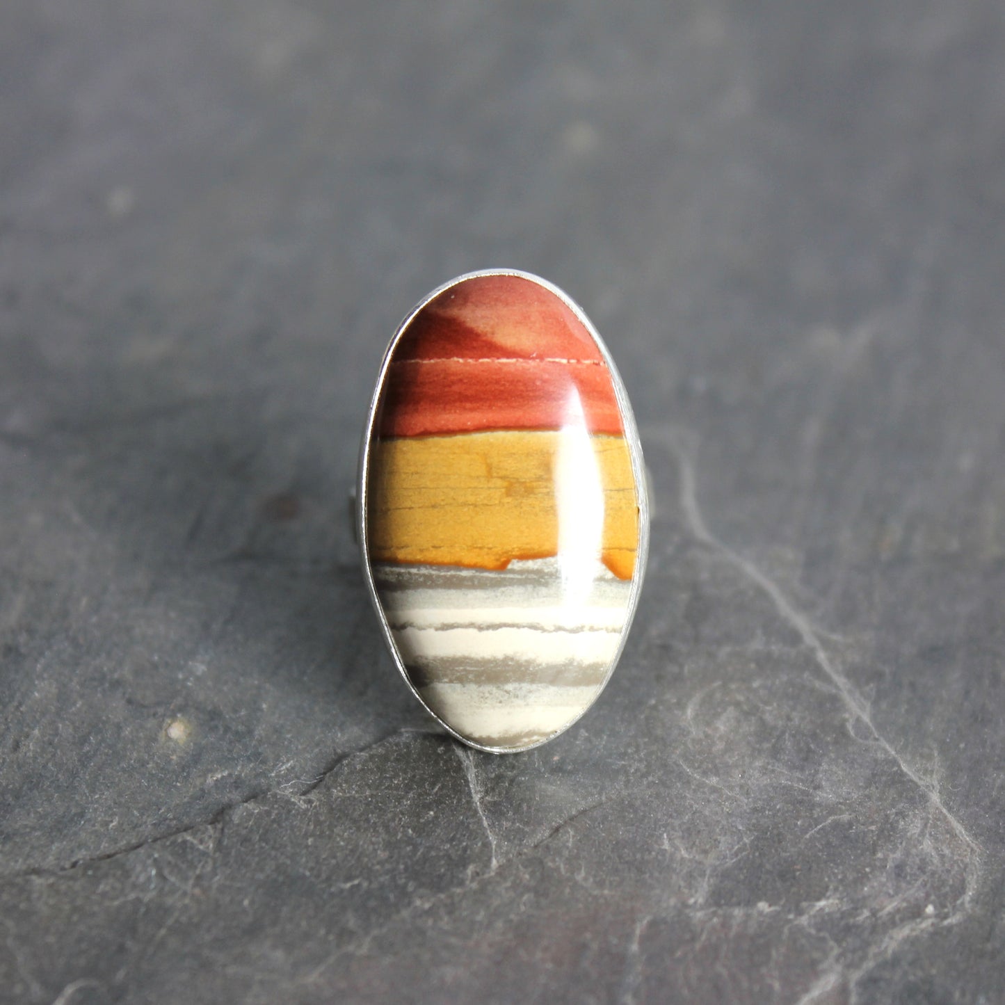 Ring with a multicolored stone on a dark gray background