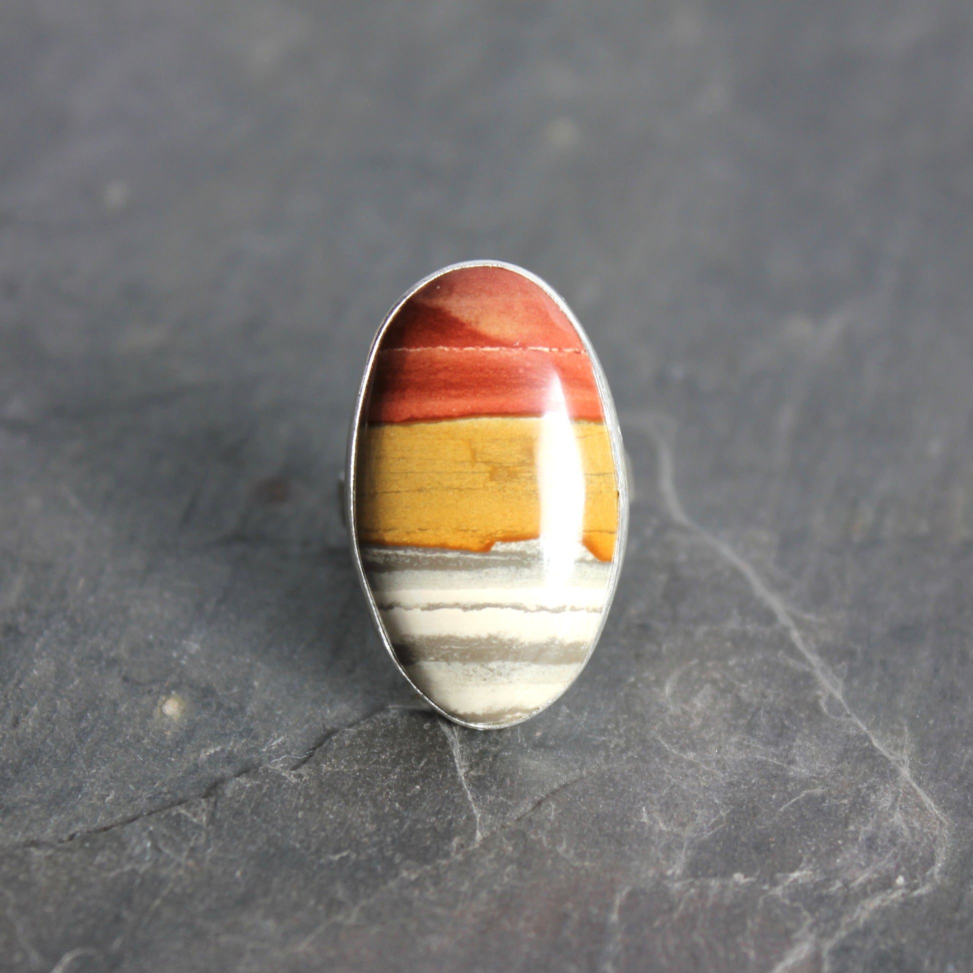 Ring with a multicolored stone on a dark gray background