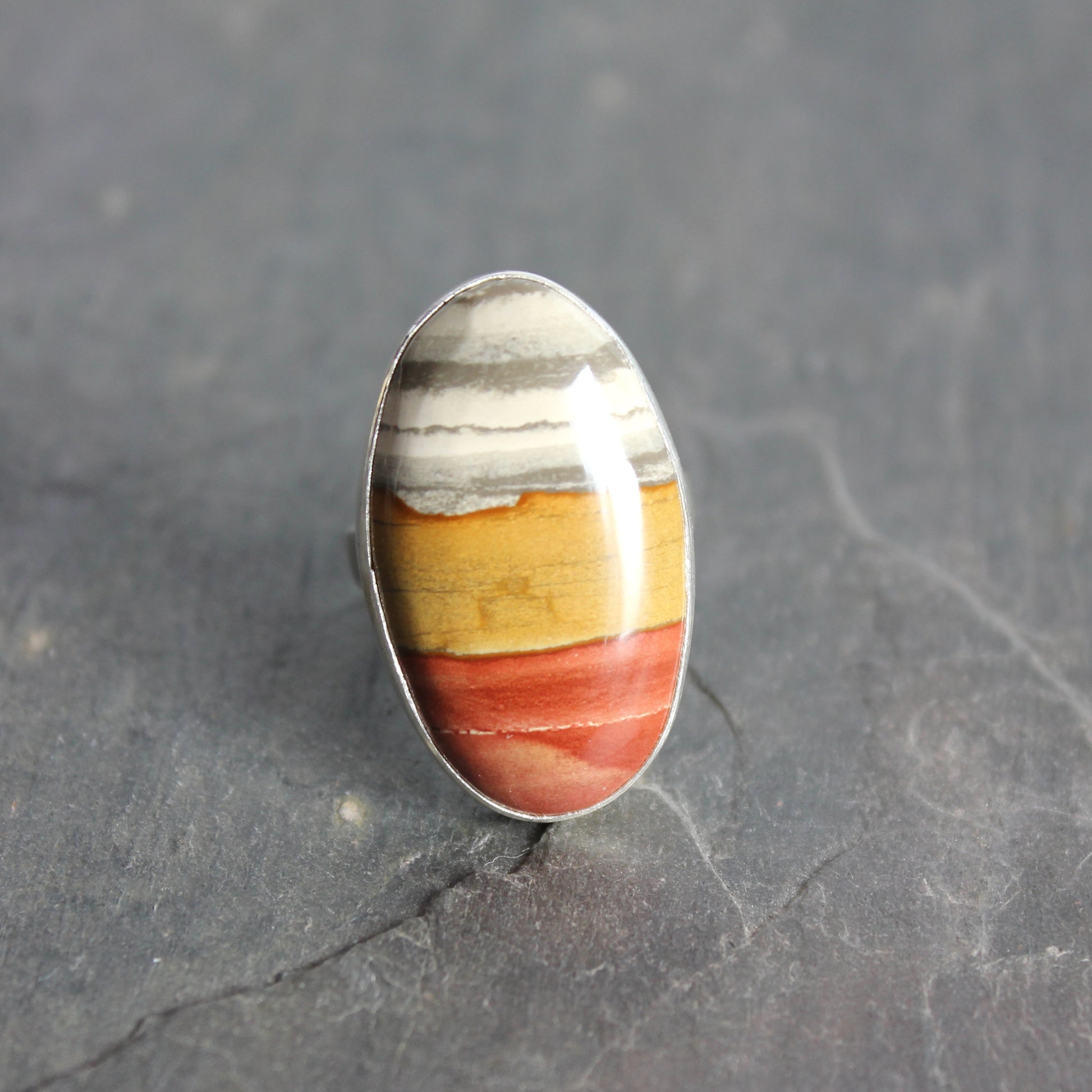 Ring with a multicolored stone on a gray surface