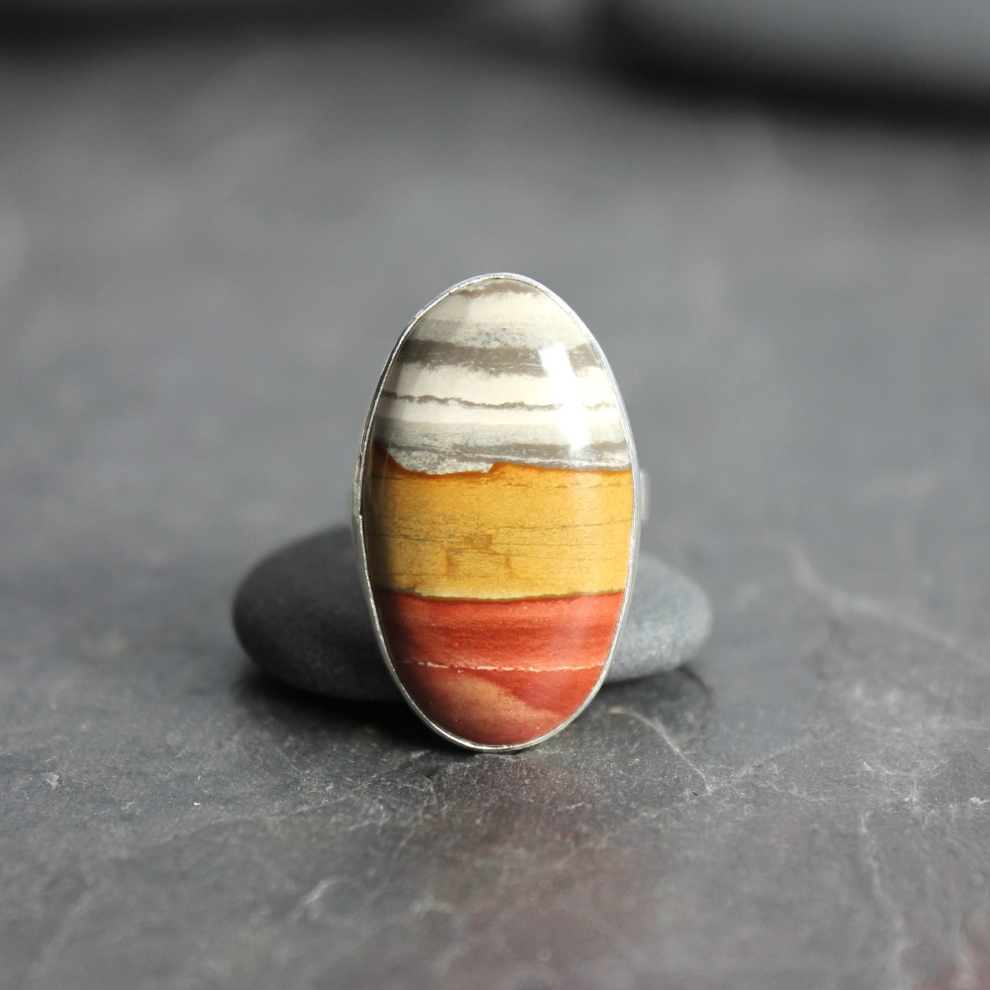 Ring with a multicolored stone on a dark gray surface