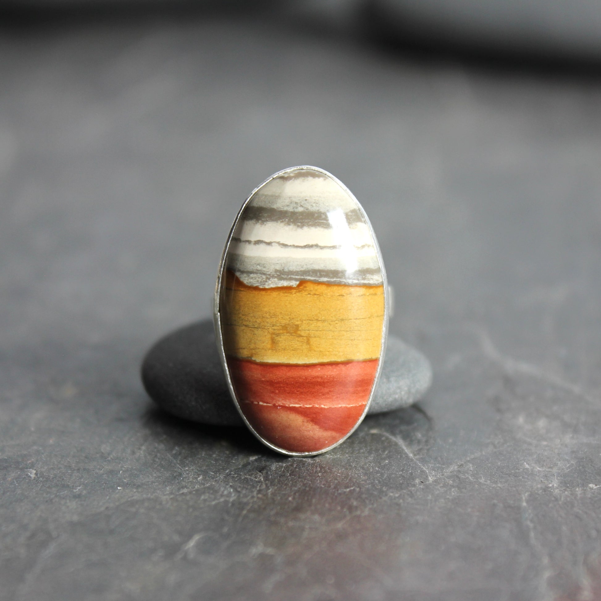 Ring with a multicolored stone on a dark gray surface