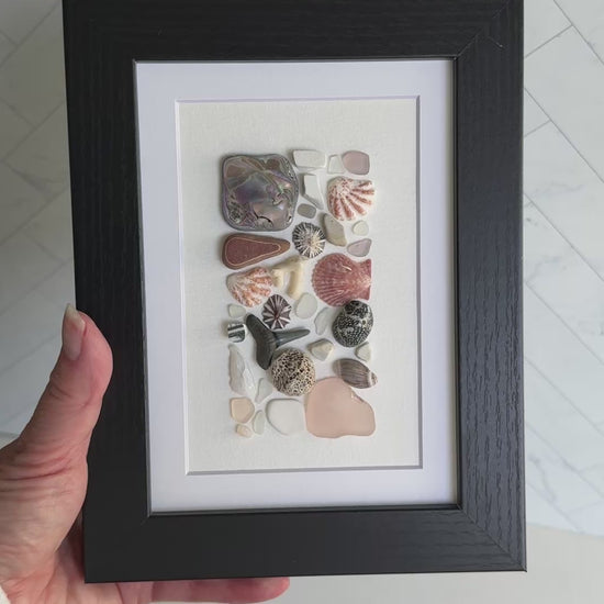 Framed artwork with sea glass and shells on a white background