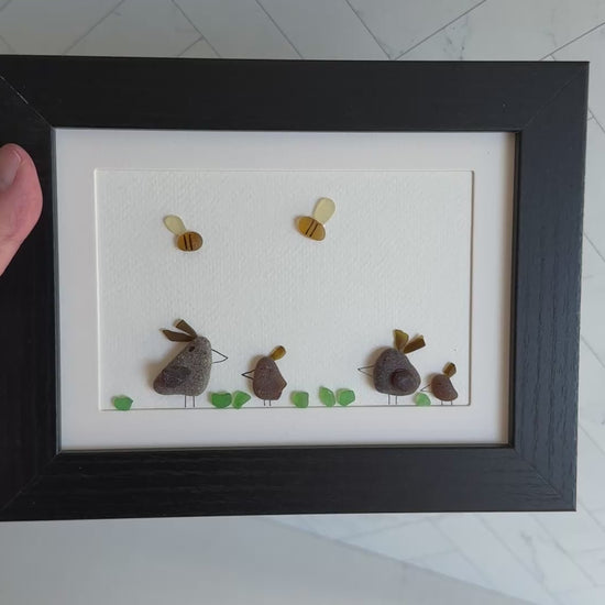 Framed sea glass artwork of hens and chickens on a white background with a black frame.