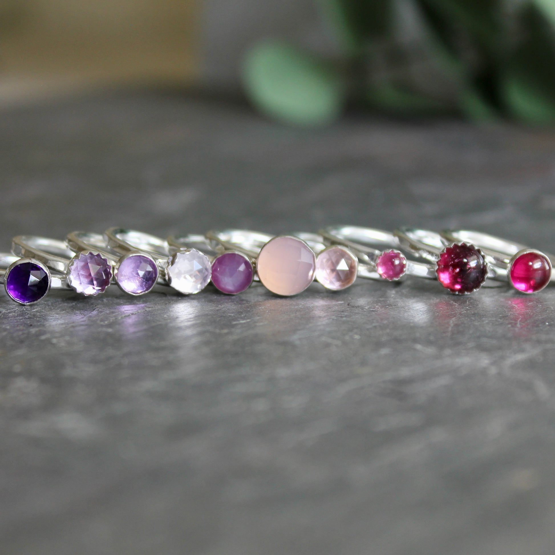 a row of gemstone stacking rings in purples and pinks