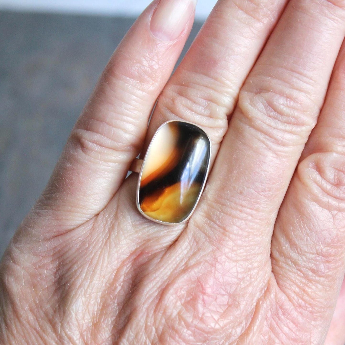 This pretty ring has a large rectangular Montana agate cabochon set in a fine and sterling silver bezel setting on a sturdy hammered band. Handmade by Will Macy in Corvallis, OR.  Size 7