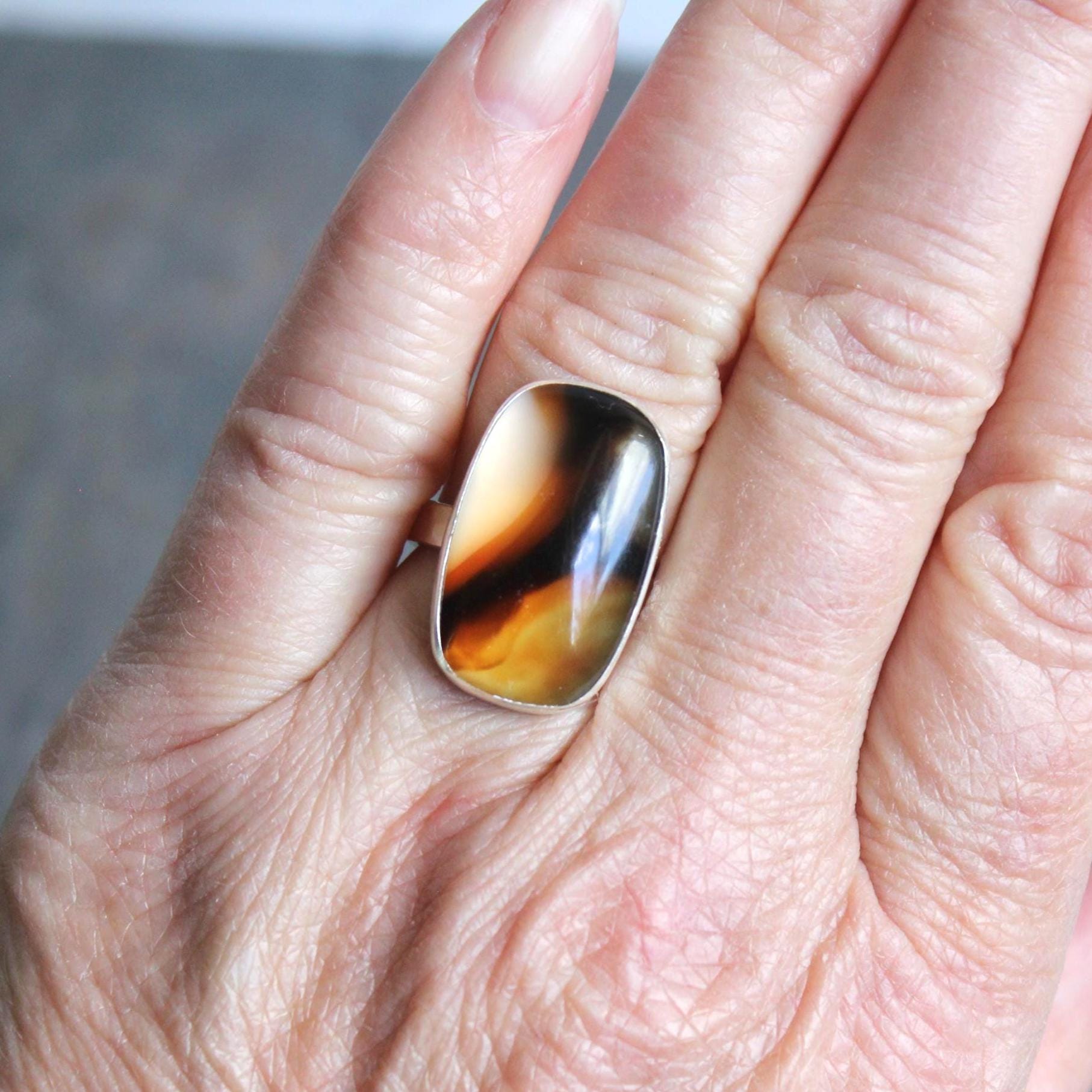 This pretty ring has a large rectangular Montana agate cabochon set in a fine and sterling silver bezel setting on a sturdy hammered band. Handmade by Will Macy in Corvallis, OR.  Size 7