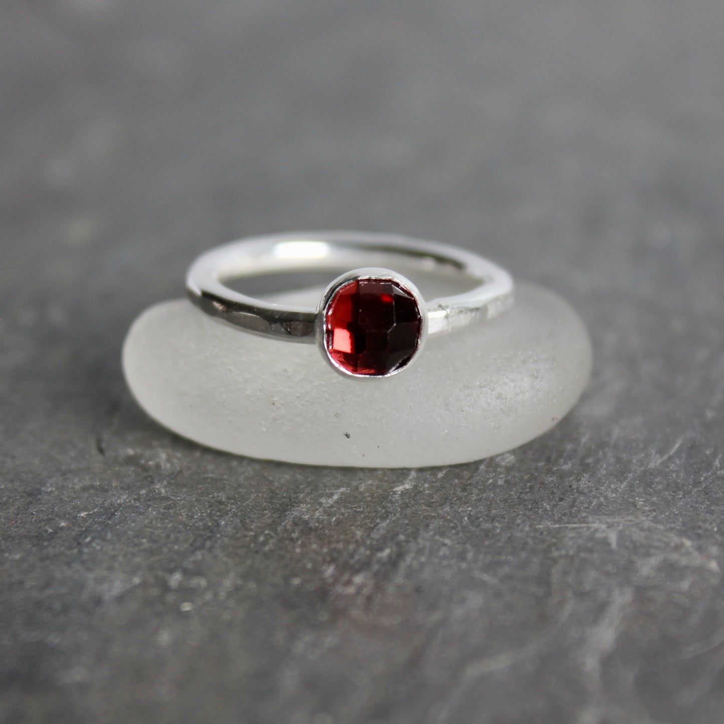 Silver ring with a red gemstone on a gray stone surface