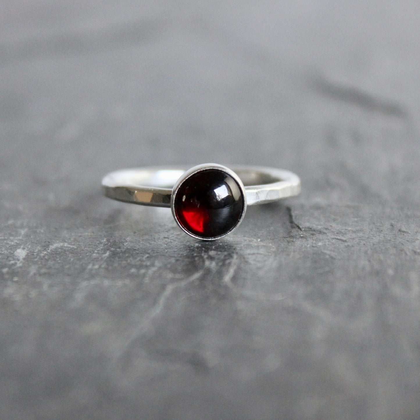 Silver ring with a black and red gemstone on a gray surface