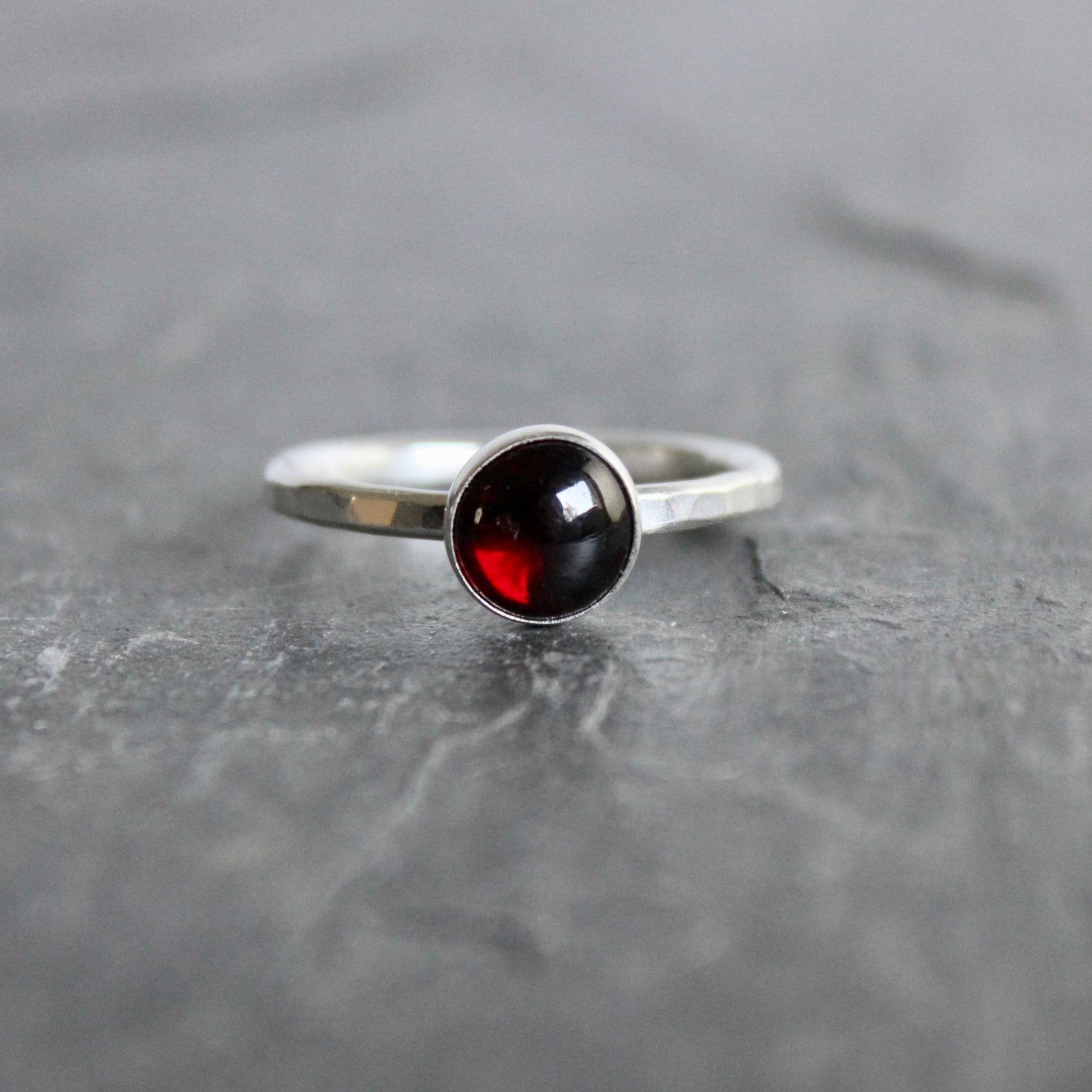 Silver ring with a black and red gemstone on a gray surface