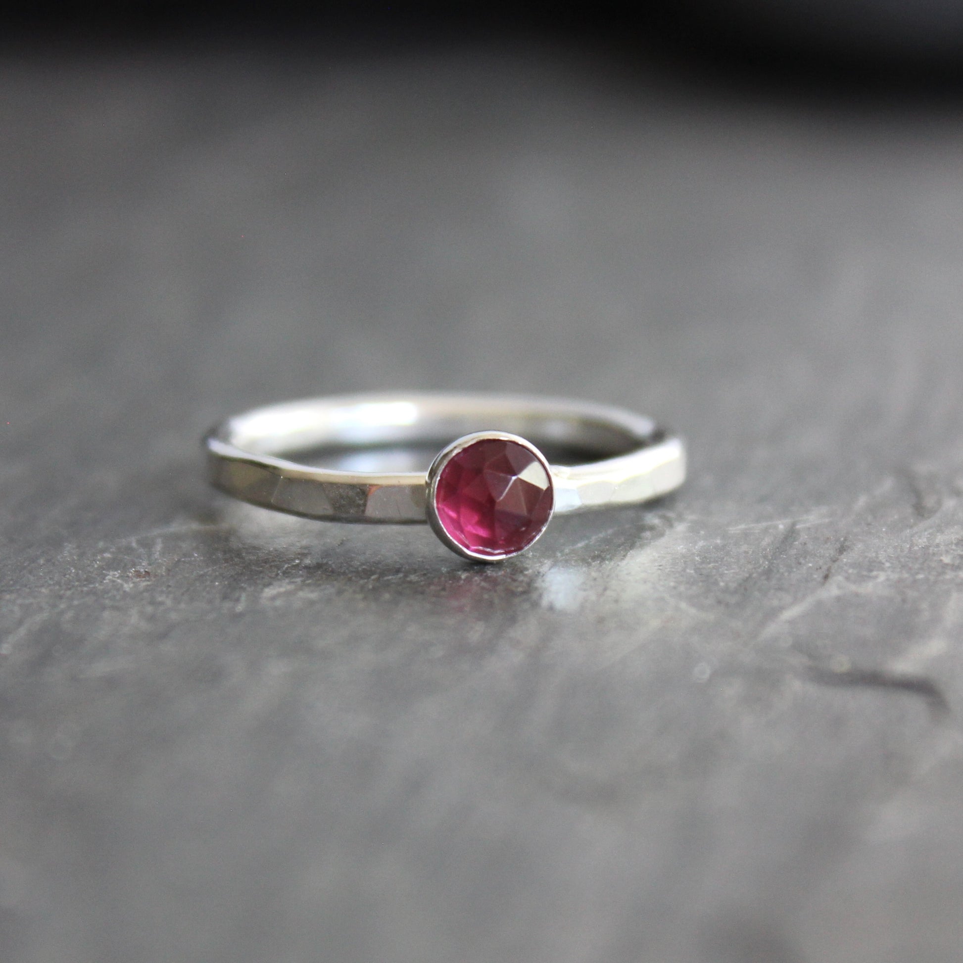 Silver ring with a red gemstone on a dark gray surface