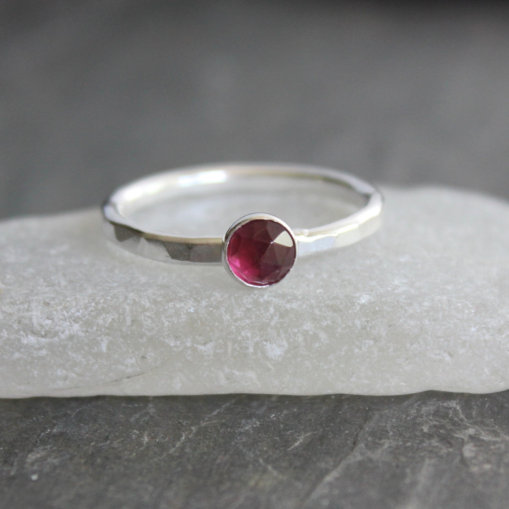Silver ring with a red gemstone on a gray stone surface