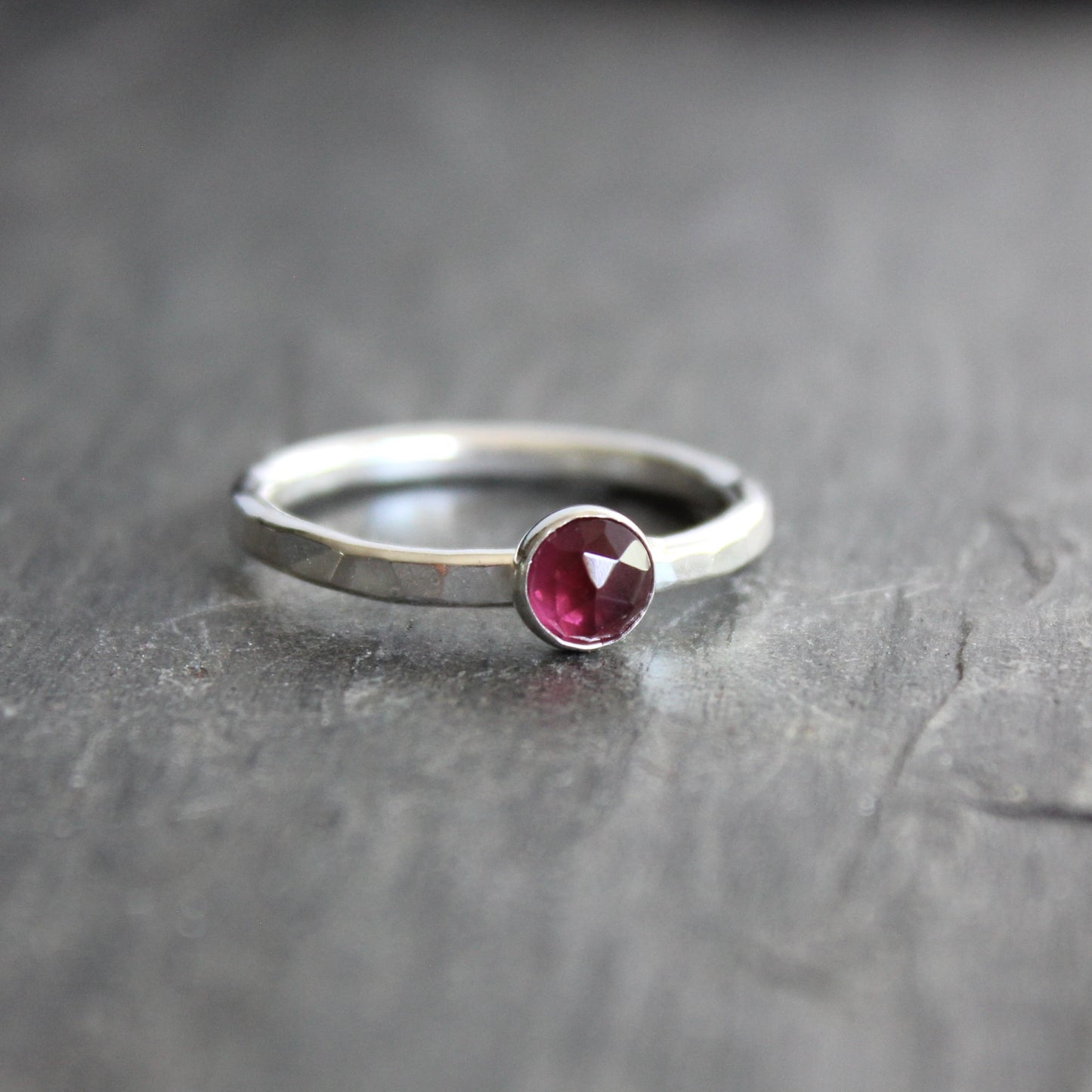 Silver ring with a red gemstone on a gray surface
