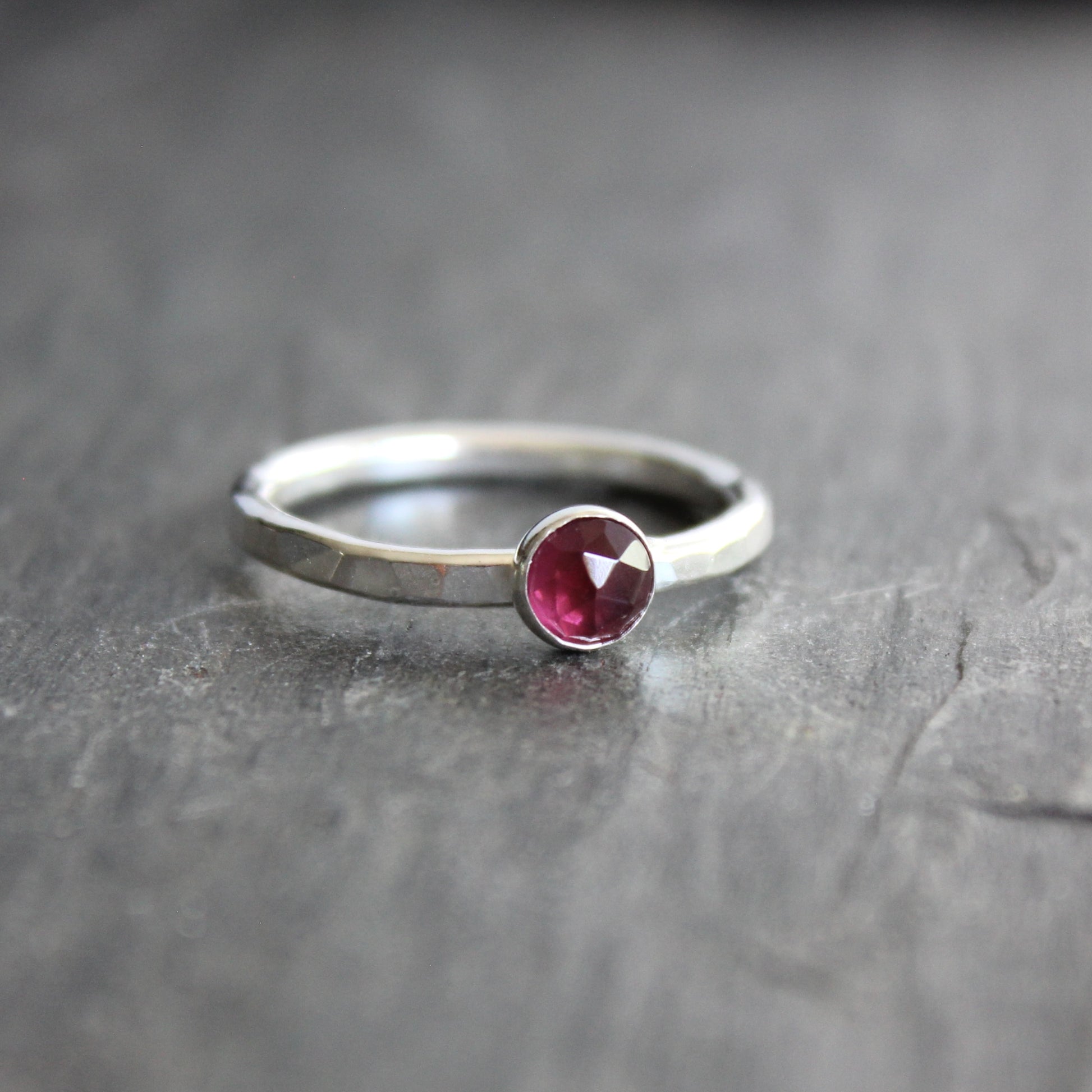 Silver ring with a red gemstone on a gray surface