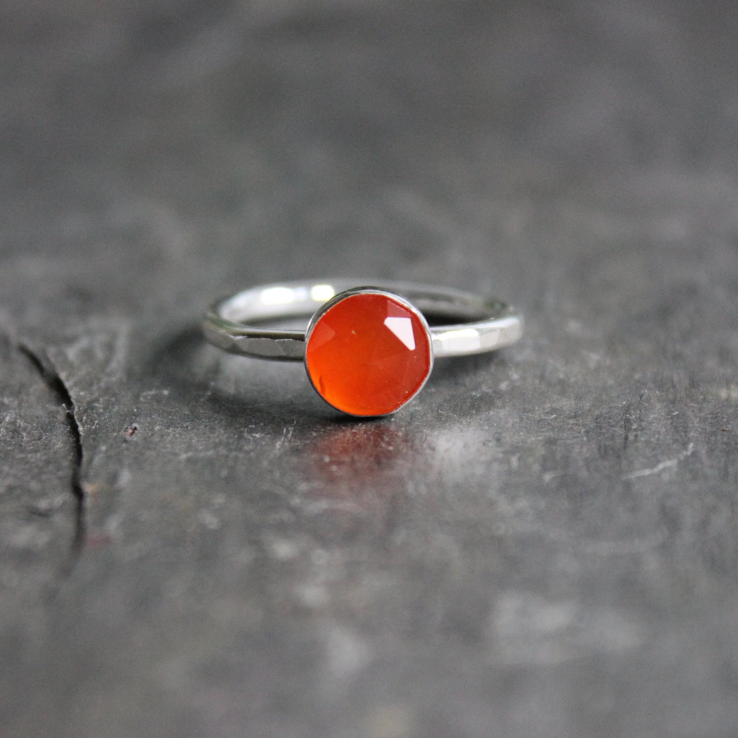Silver ring with an orange carnelian gemstone on a dark surface
