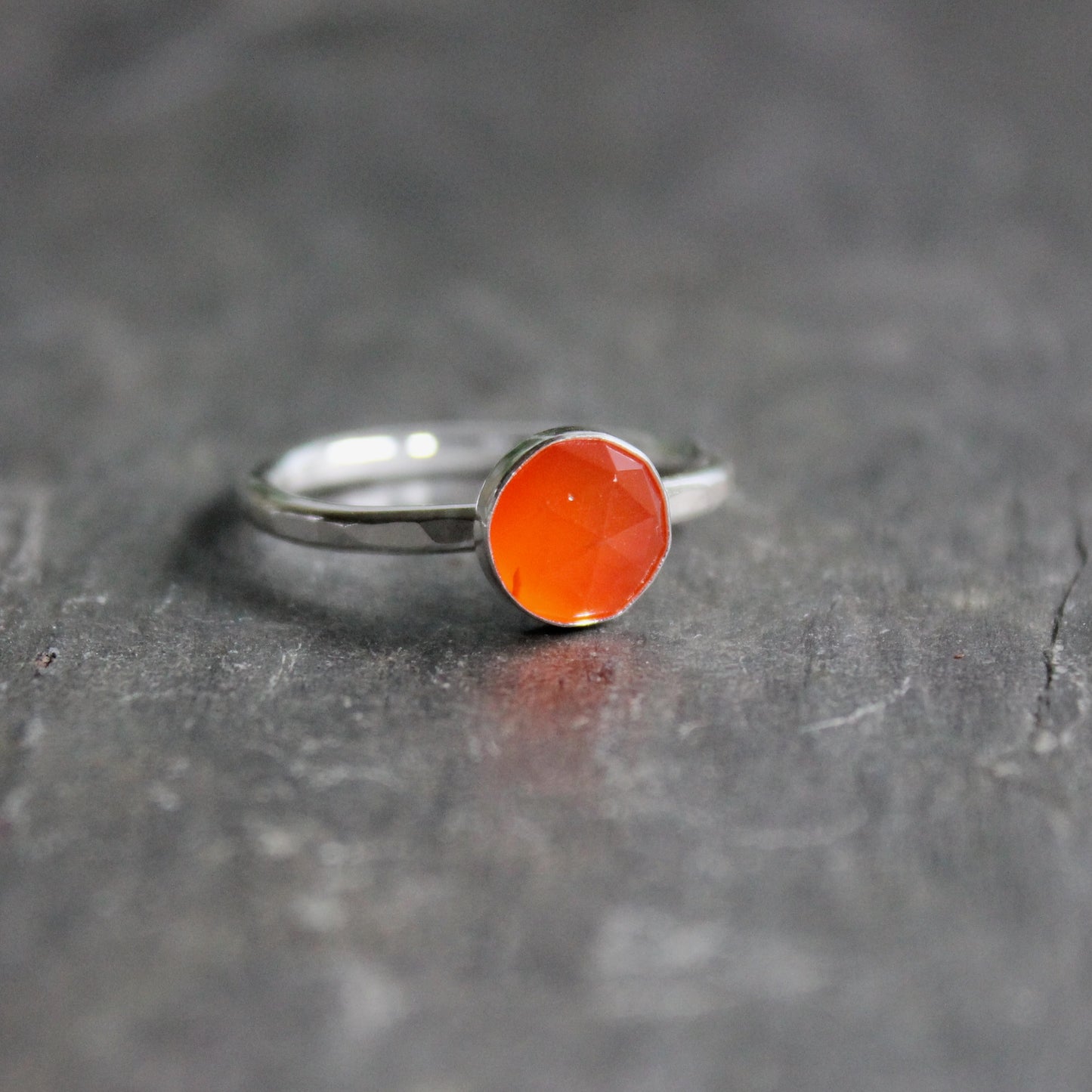 Silver ring with a carnelian  gemstone on a dark gray surface