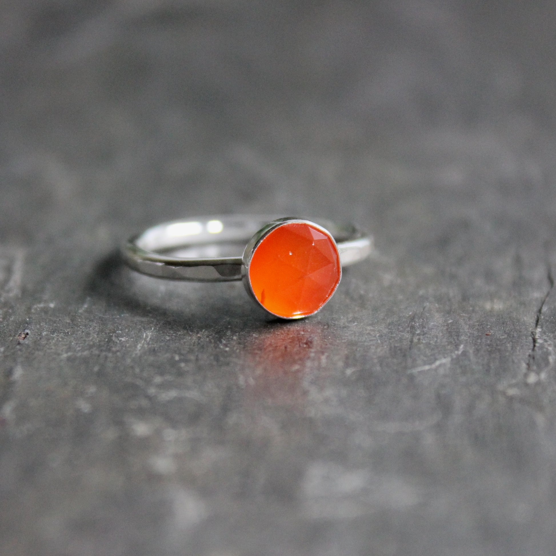 Silver ring with a carnelian  gemstone on a dark gray surface