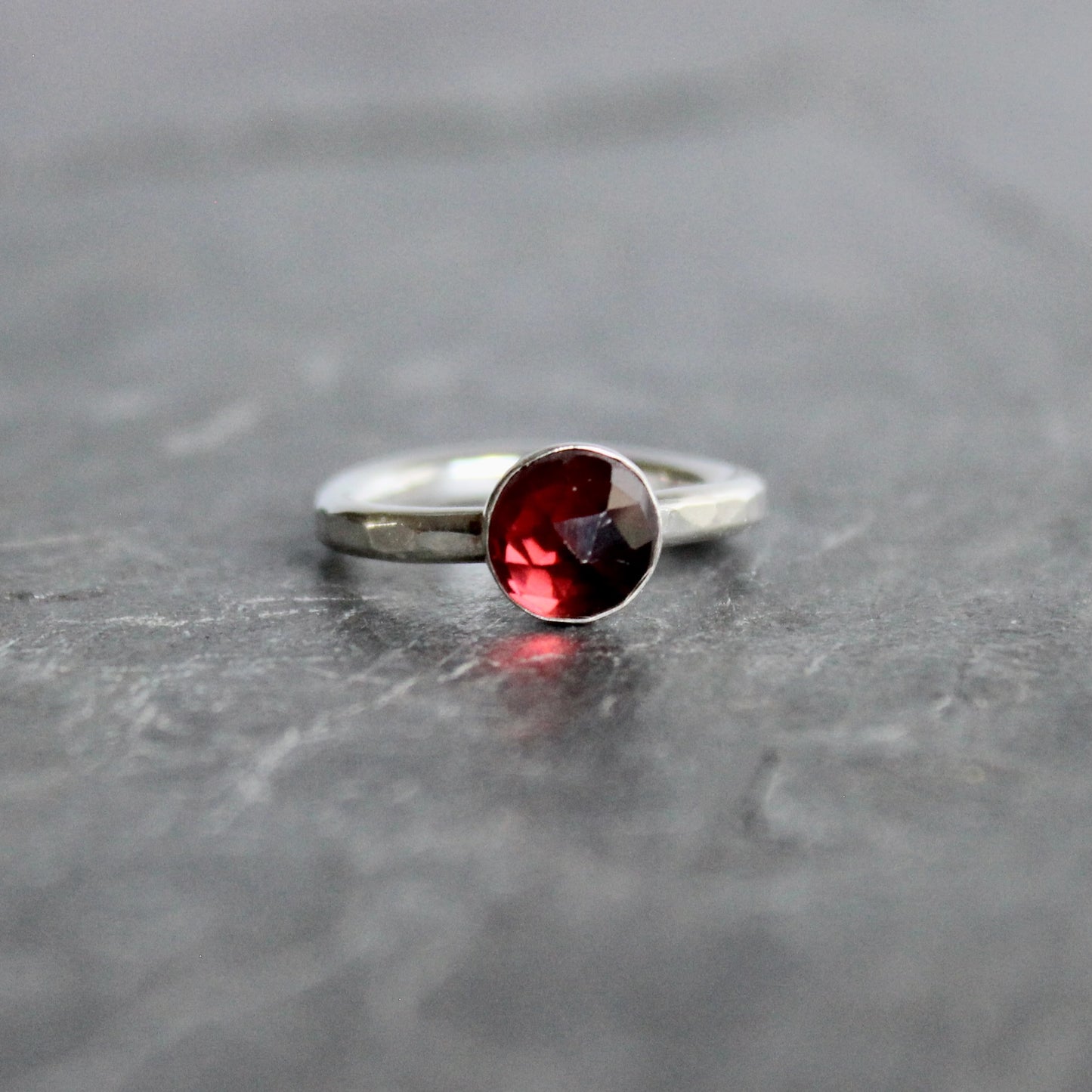 Silver ring with a red gemstone on a gray surface