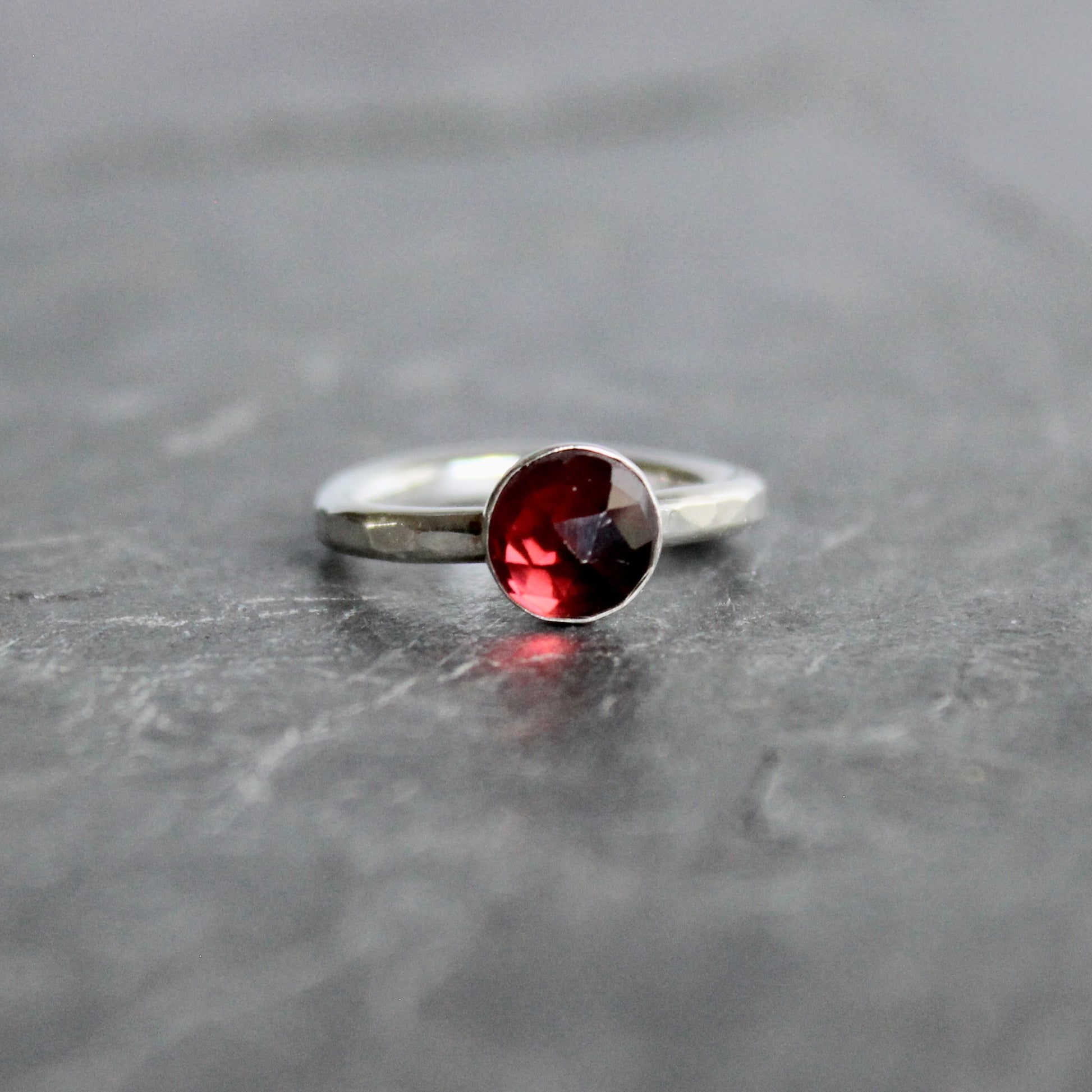 Silver ring with a red gemstone on a gray surface