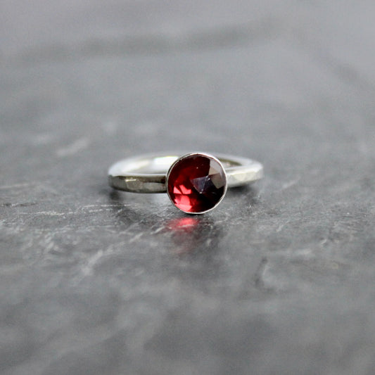 Silver ring with a red gemstone on a gray surface