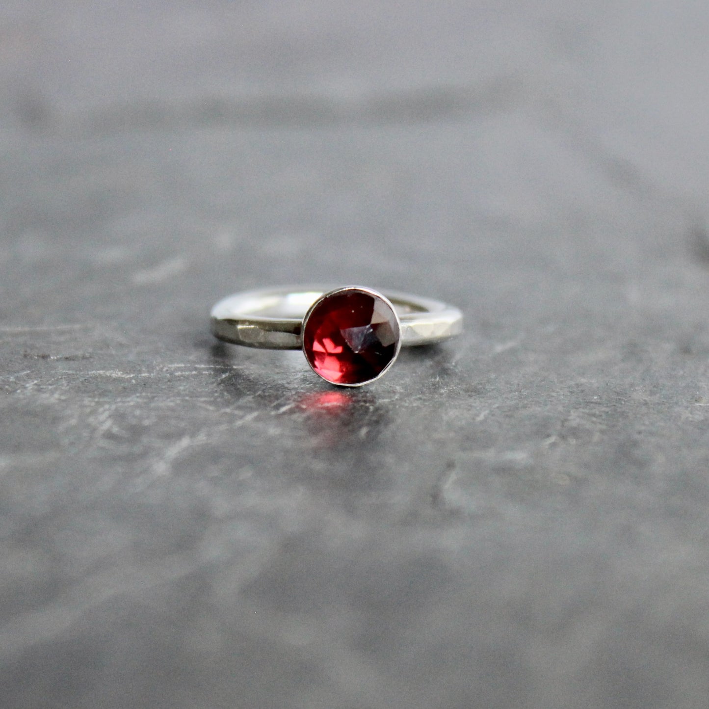 Silver ring with a red gemstone on a gray surface