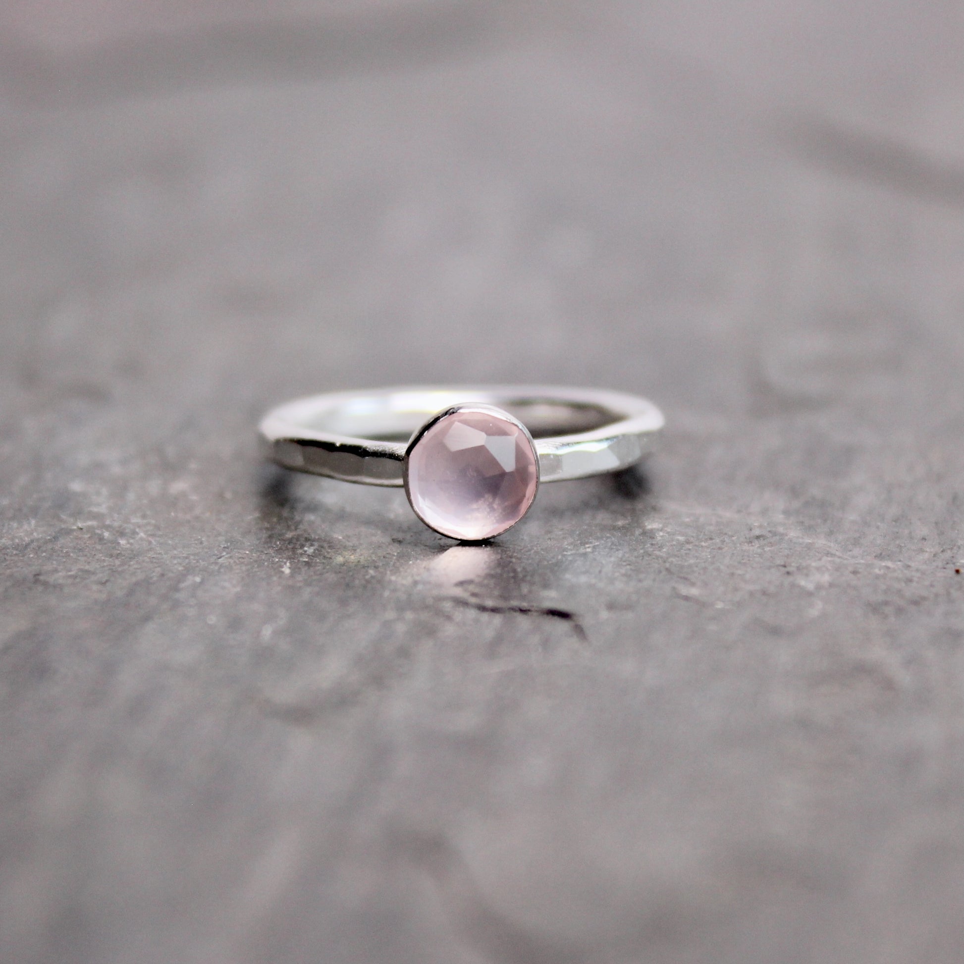Silver ring with a pink gemstone on a gray surface