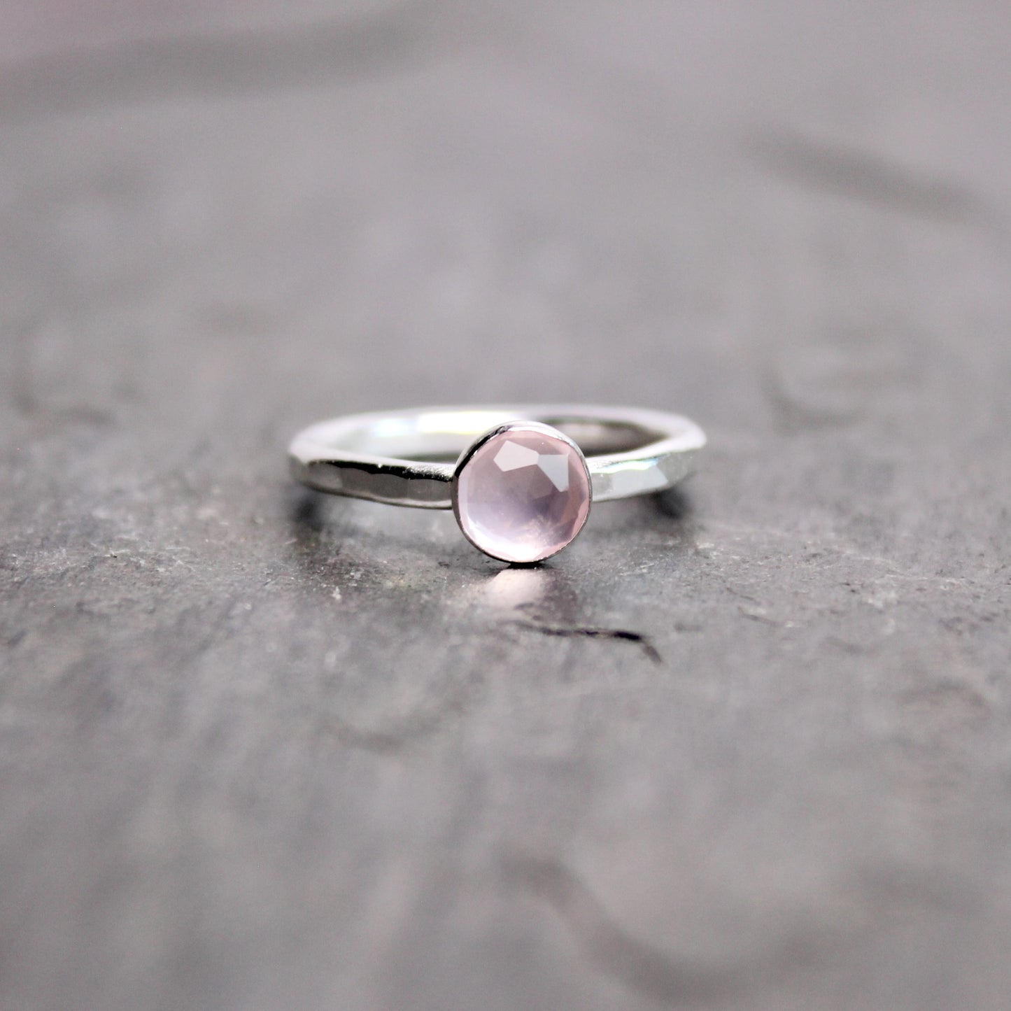 Silver ring with a pink gemstone on a gray surface