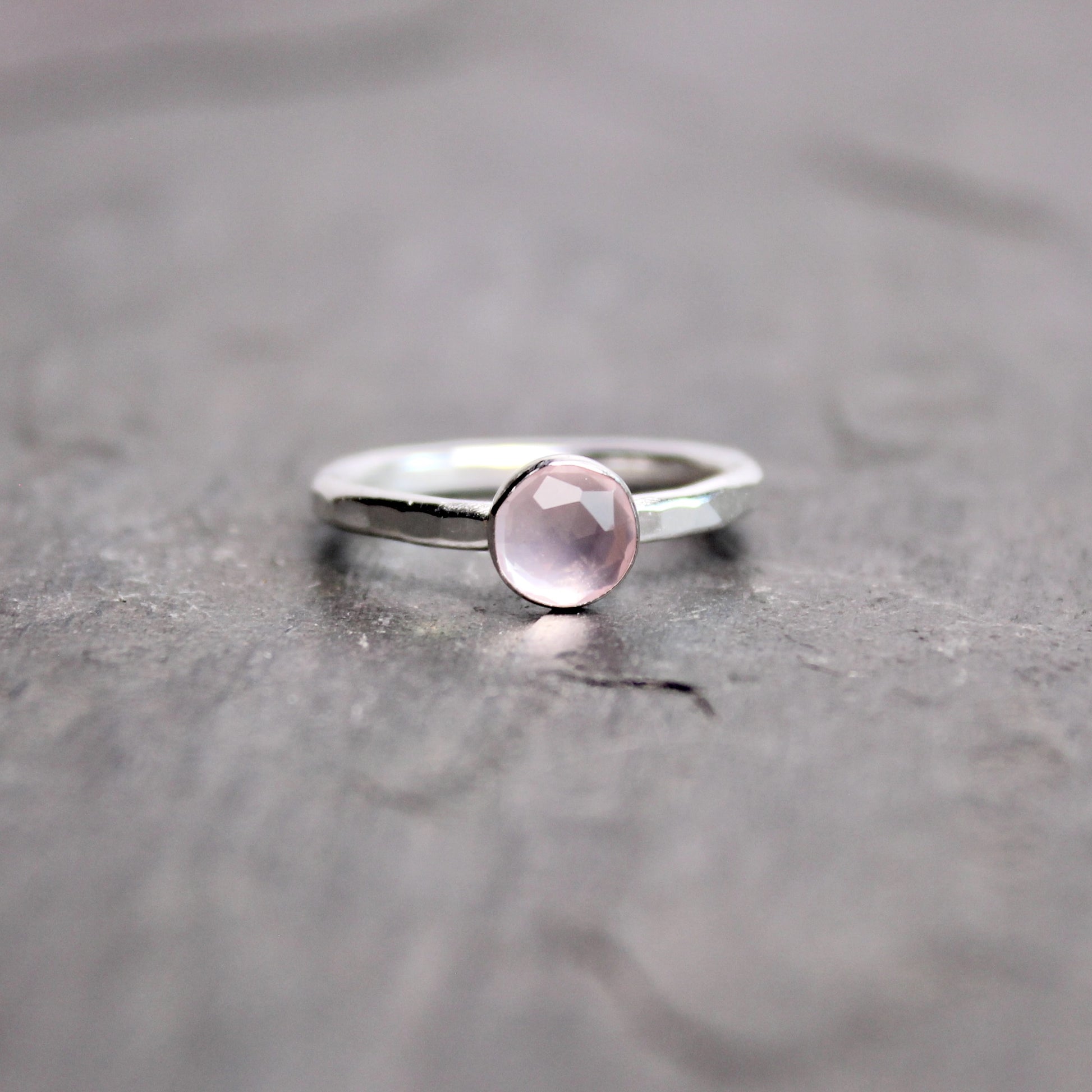 Silver ring with a pink gemstone on a gray surface