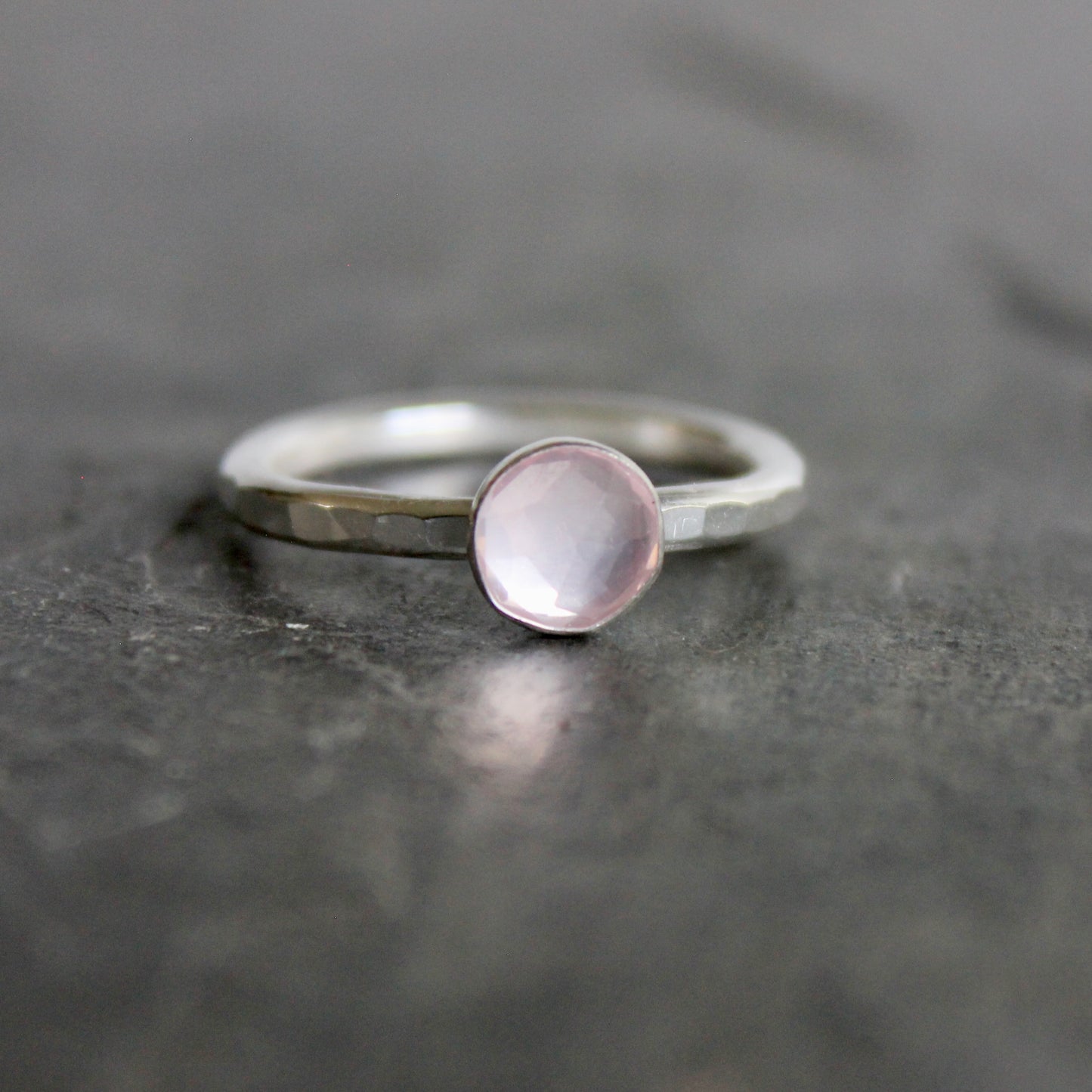 Silver ring with a pink gemstone on a dark gray surface