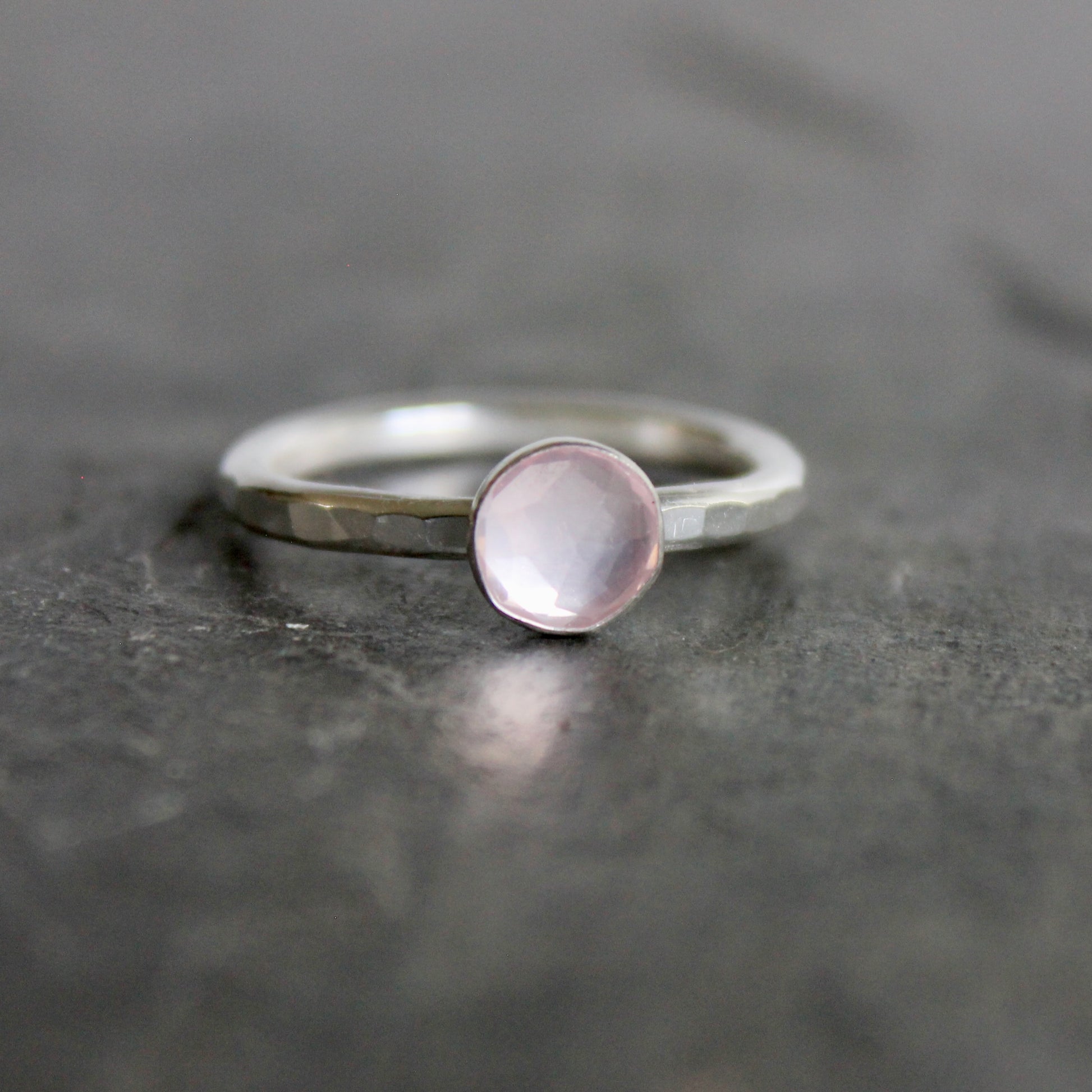Silver ring with a pink gemstone on a dark gray surface