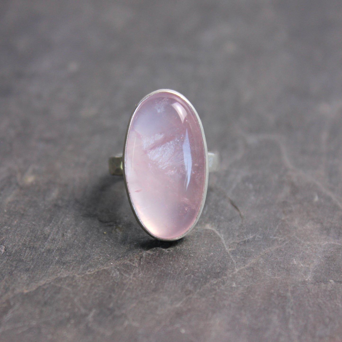 Ring with a rose quartz oval stone on a dark gray surface