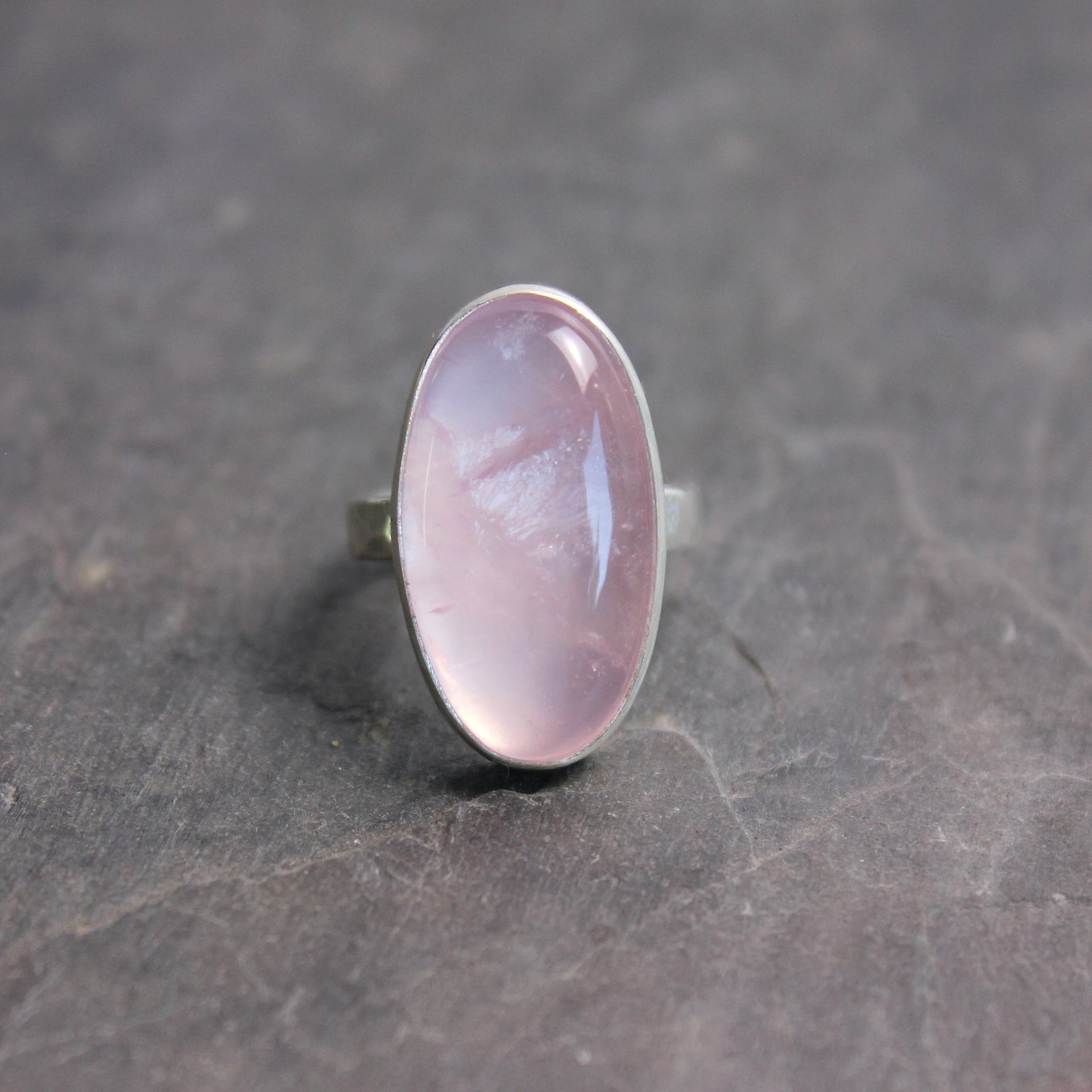 Ring with a rose quartz oval stone on a dark gray surface