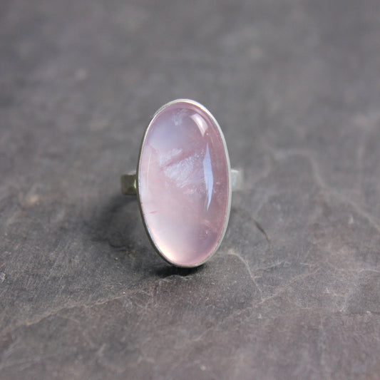 Ring with a rose quartz oval stone on a dark gray surface