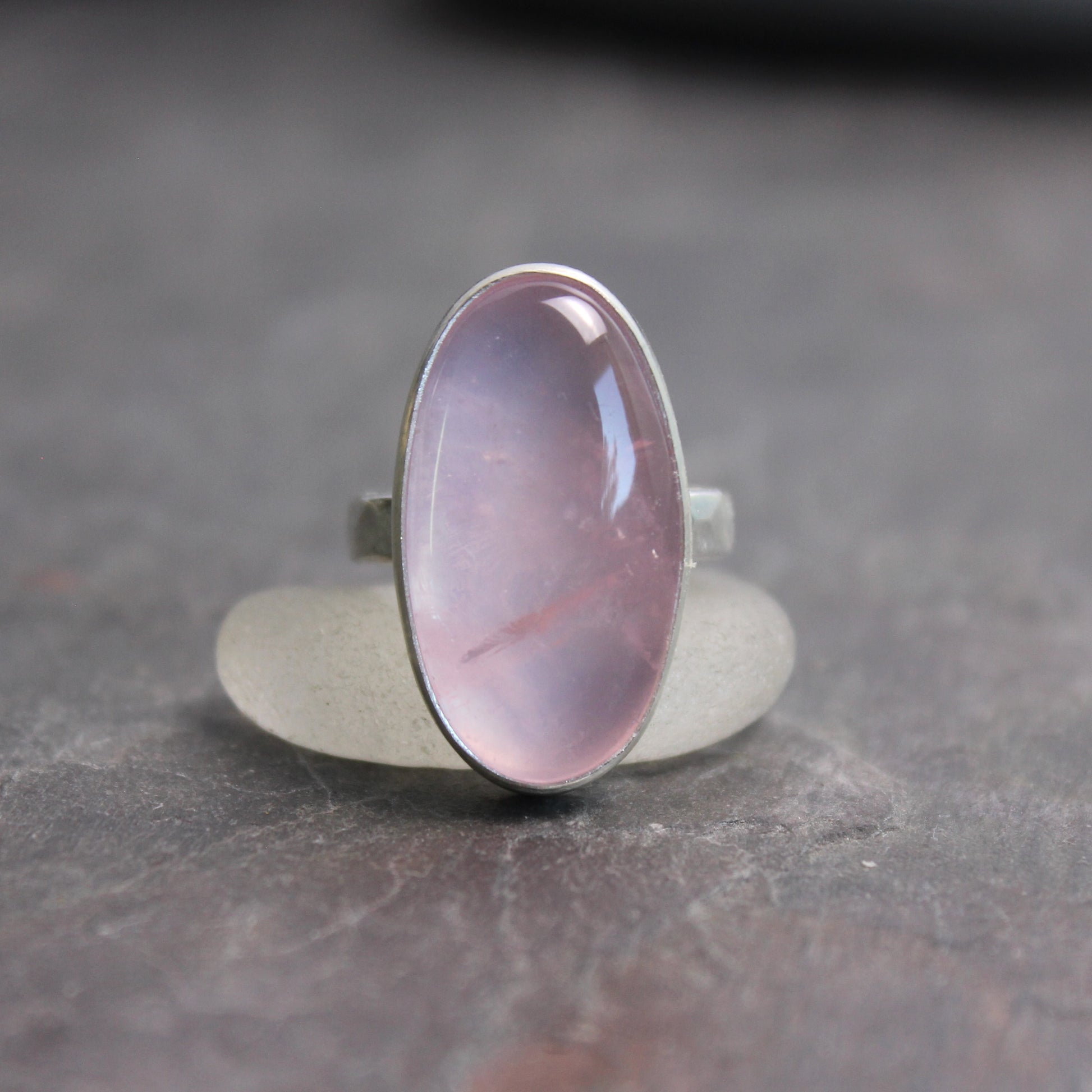 Ring with a rose quartz oval stone on a dark gray surface