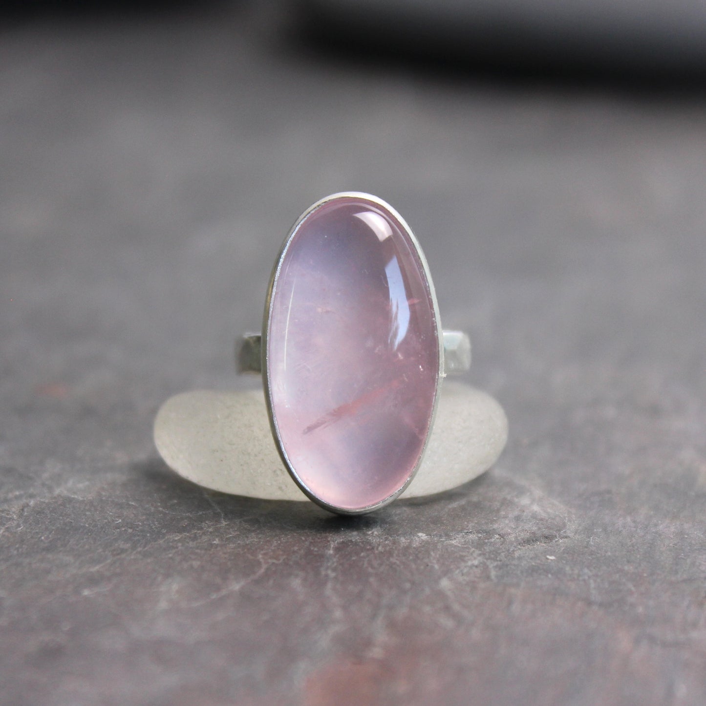 Ring with a rose quartz oval stone on a dark gray surface