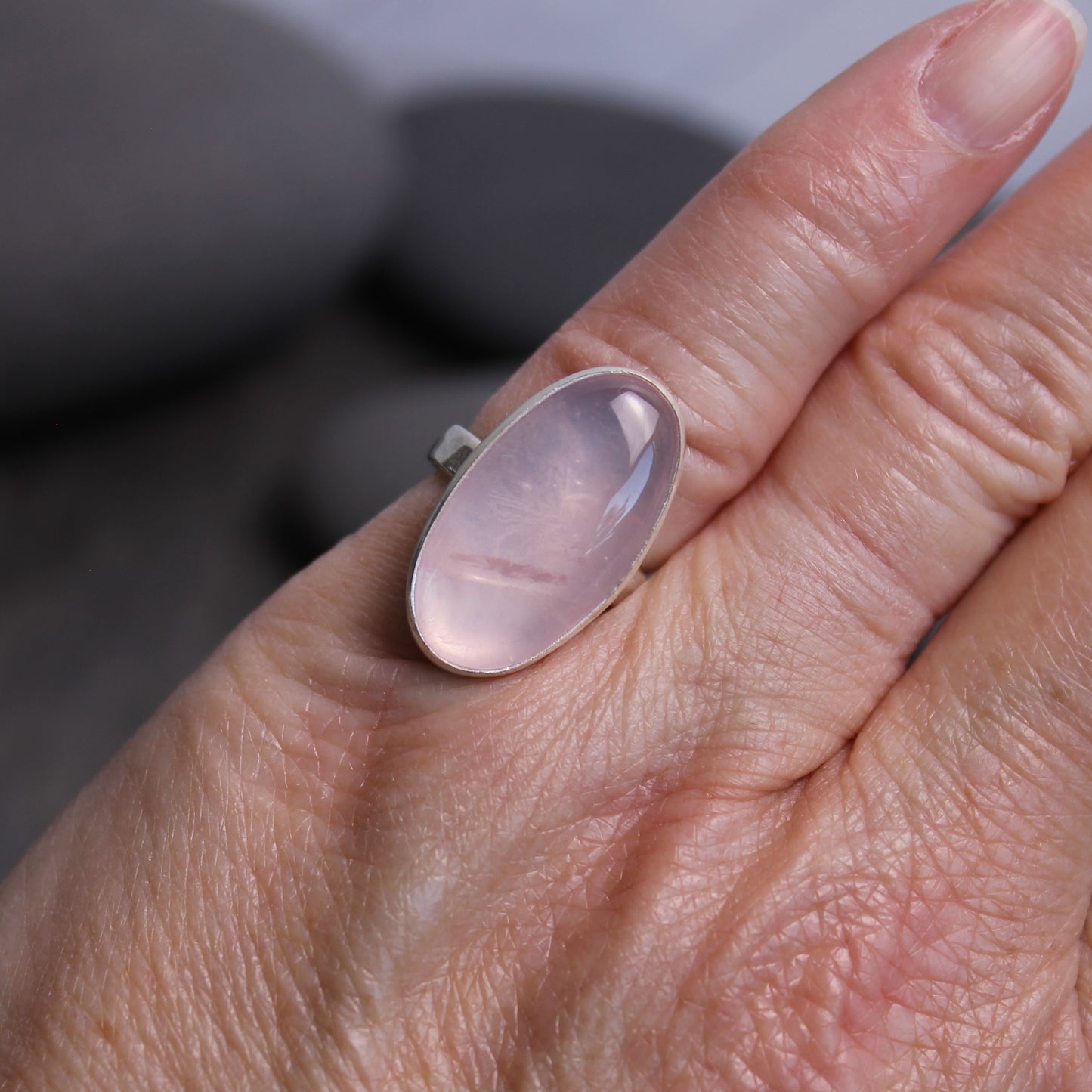 Ring with a rose quartz oval stone on a finger
