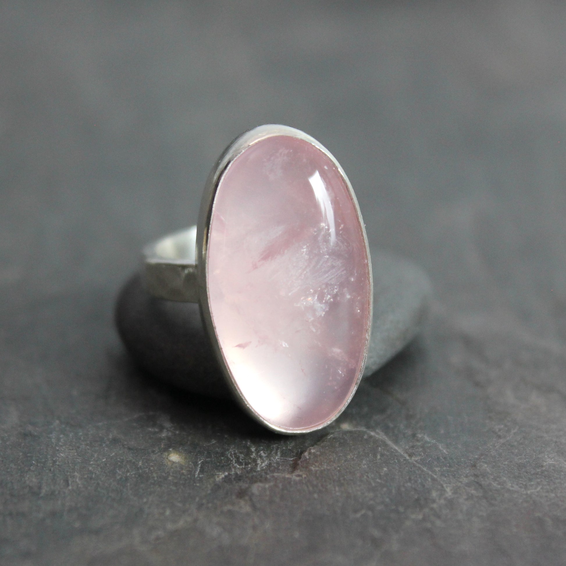 Ring with a rose quartz oval stone on a dark gray surface