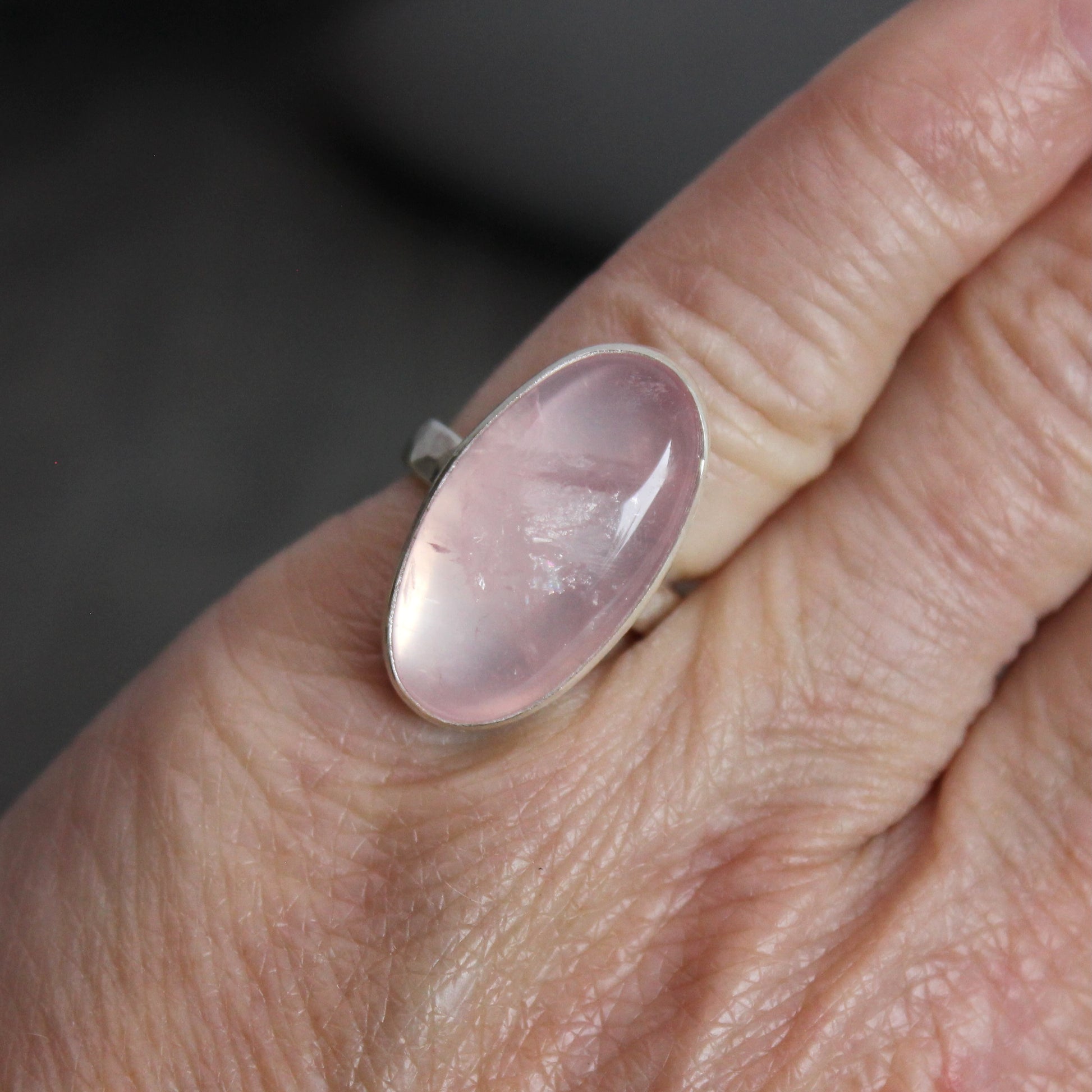 Ring with a rose quartz oval stone on a finger