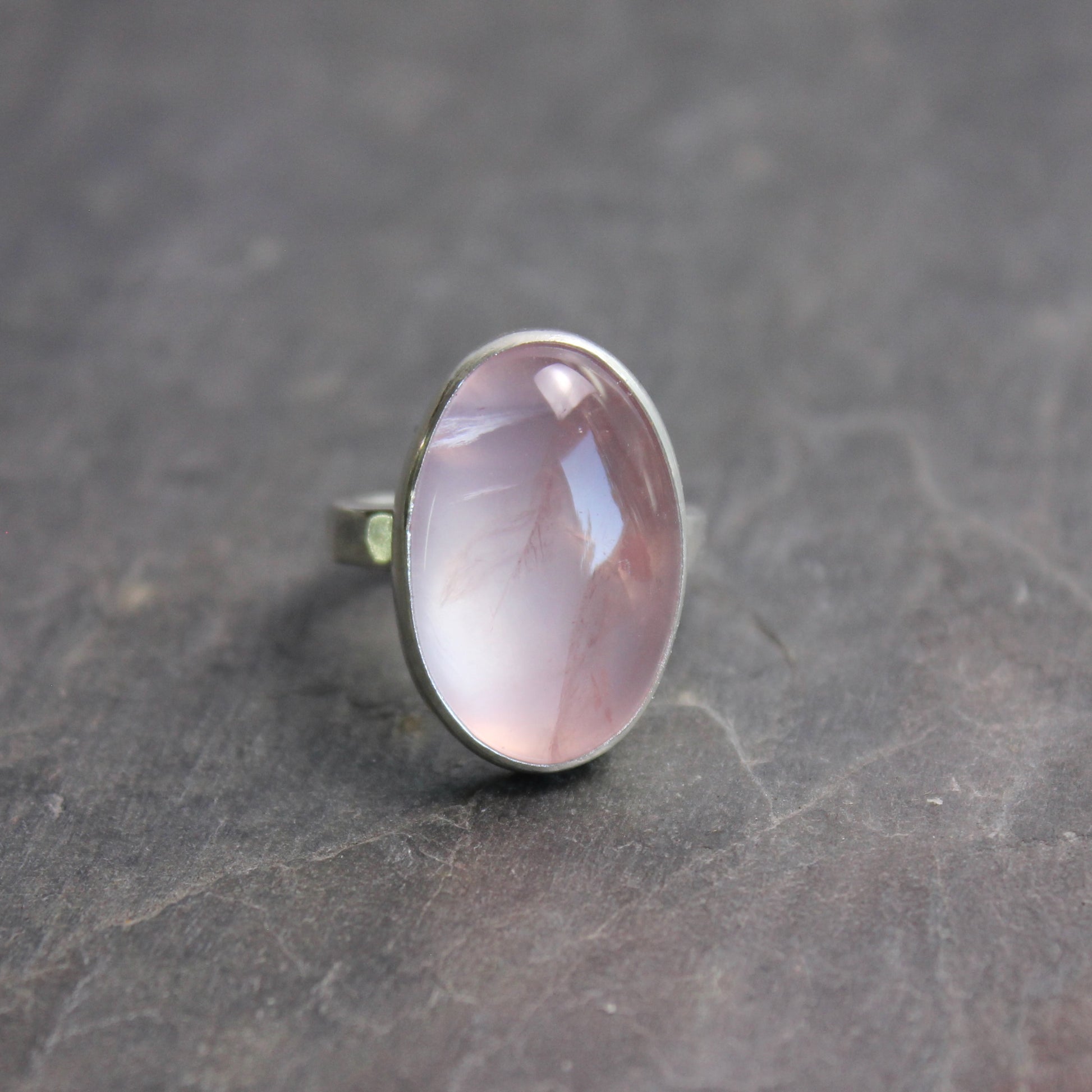 Ring with a rose quartz stone on a dark gray surface