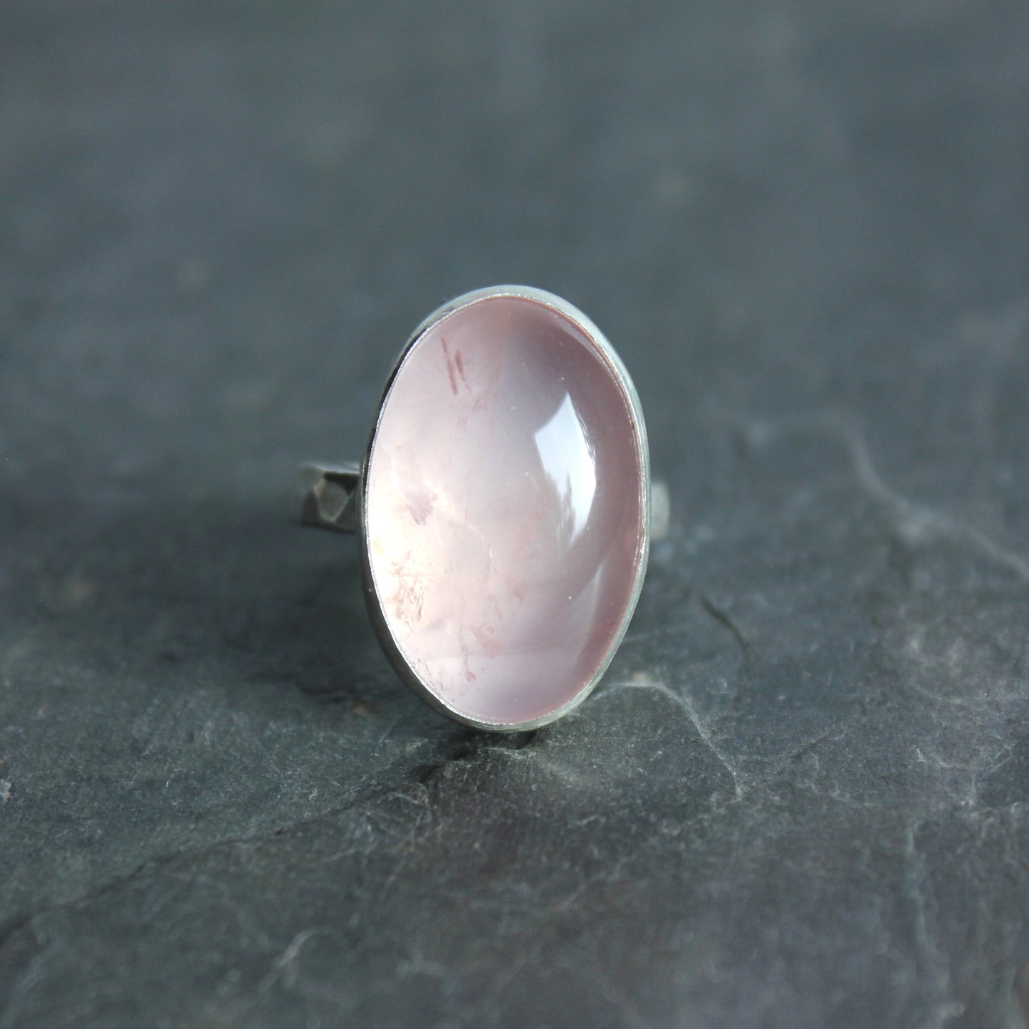 Silver ring with a pink rose quartz stone on a dark gray surface