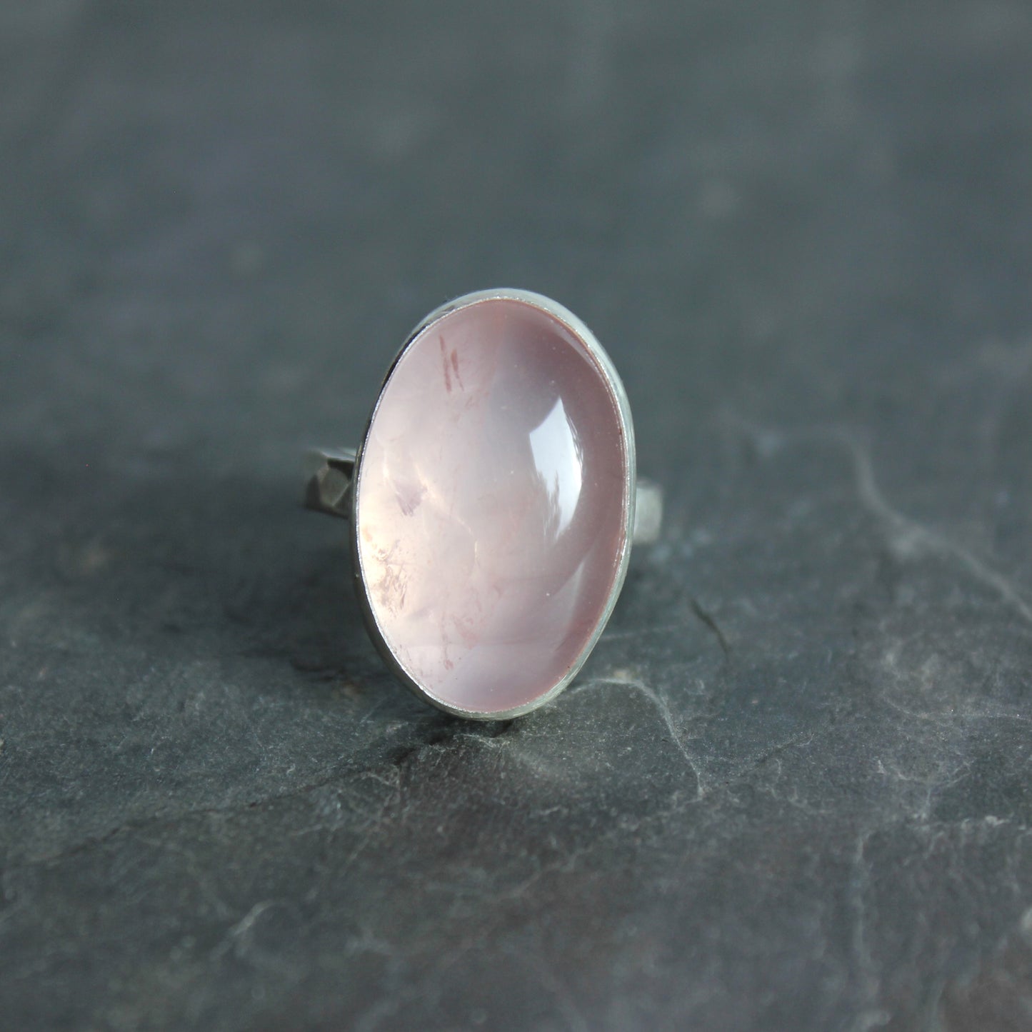 Ring with a pink rose quartz stone on a dark gray surface