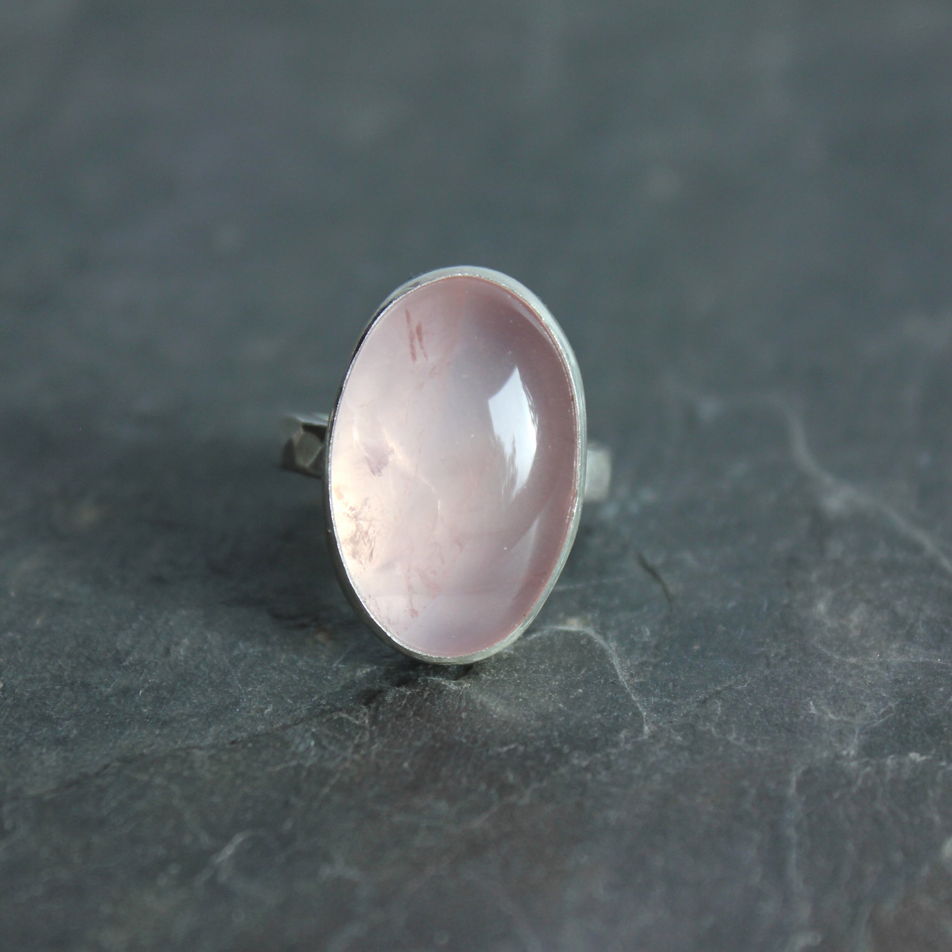 Ring with a pink rose quartz stone on a dark gray surface