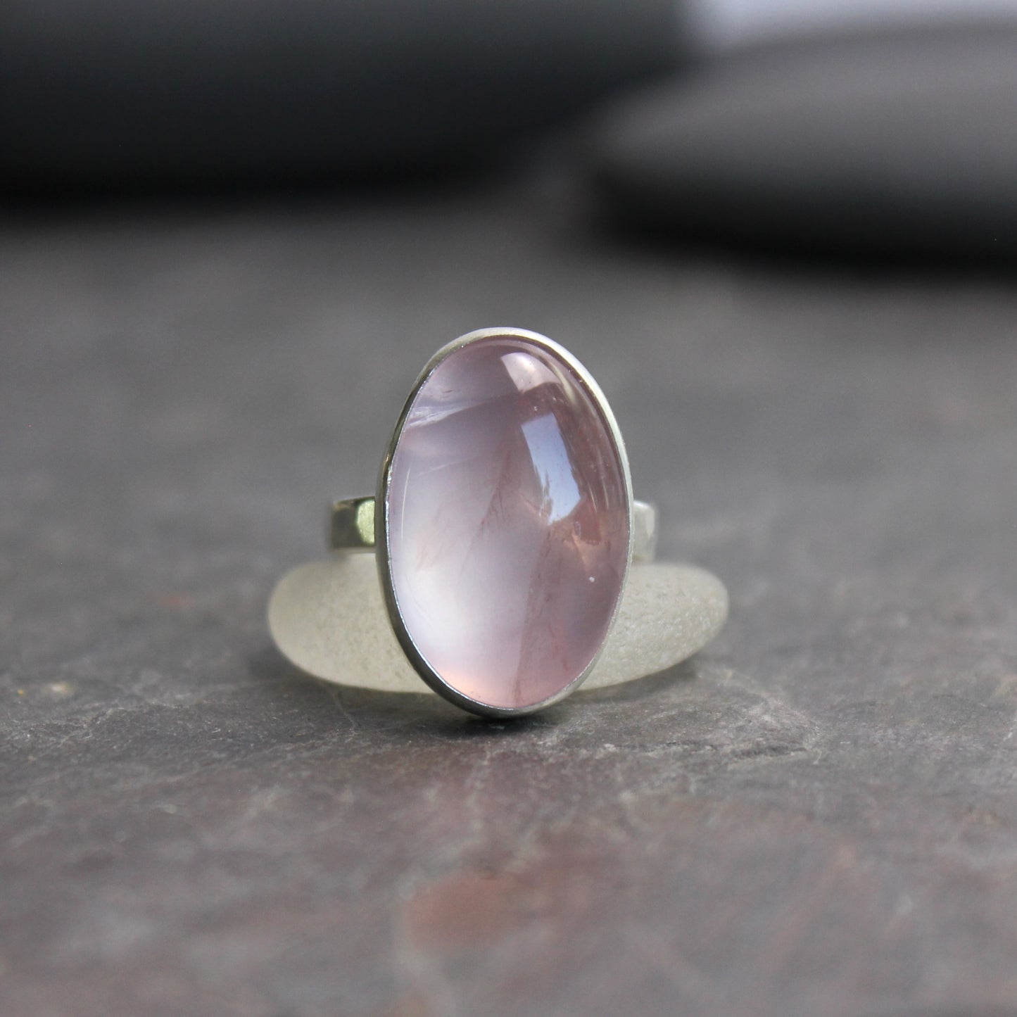 Silver ring with a pink rose quartz gemstone on a dark surface