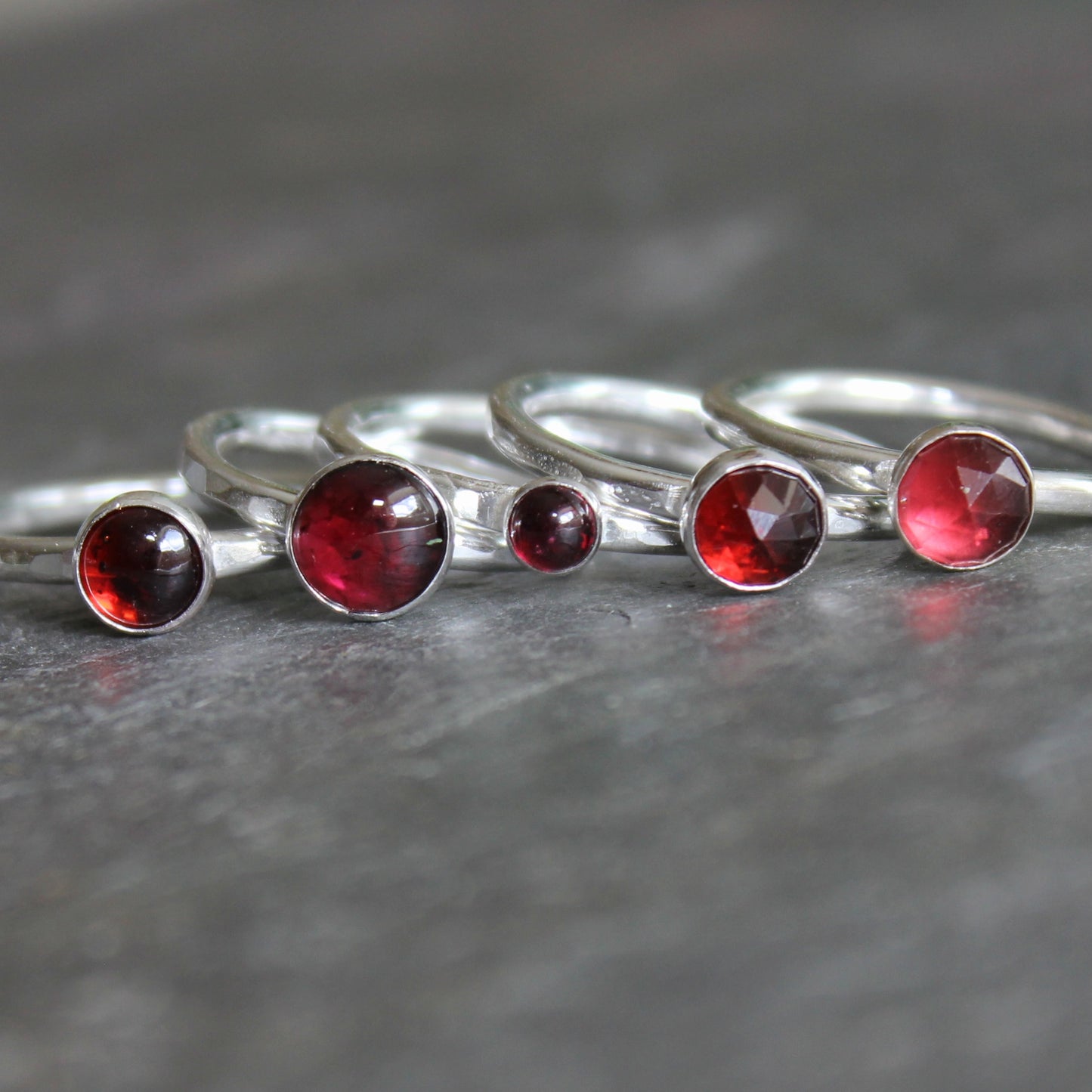 Silver rings with red gemstones on a gray surface