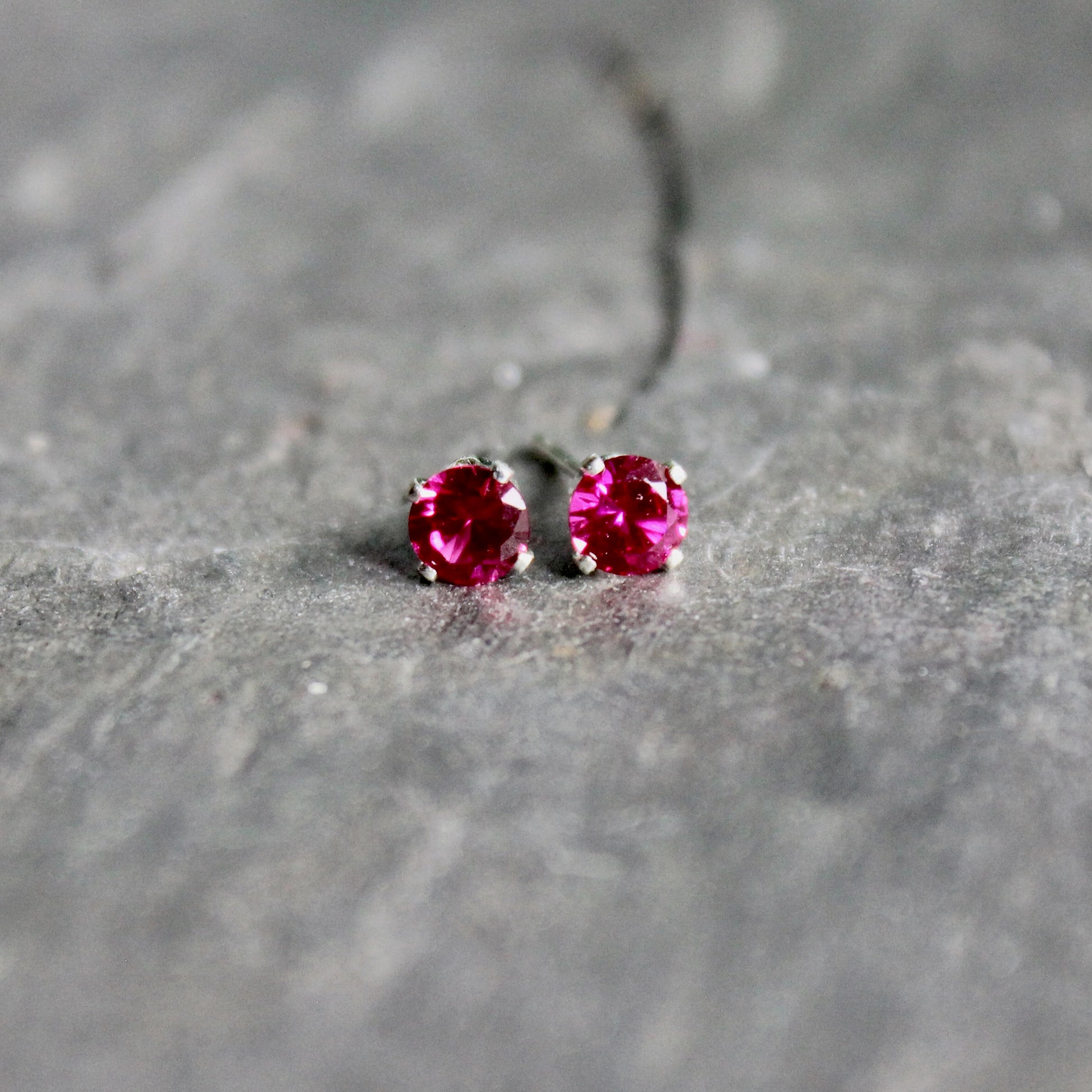 These stud earrings have 4mm round faceted lab created ruby gemstones set in sterling silver 4-prong stud earring settings with earring backs.