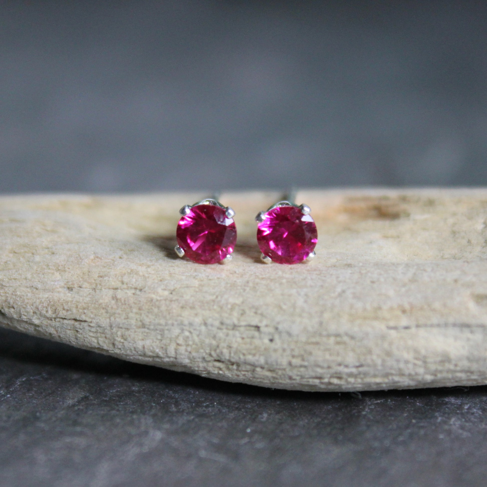 These stud earrings have 4mm round faceted lab created ruby gemstones set in sterling silver 4-prong stud earring settings with earring backs.