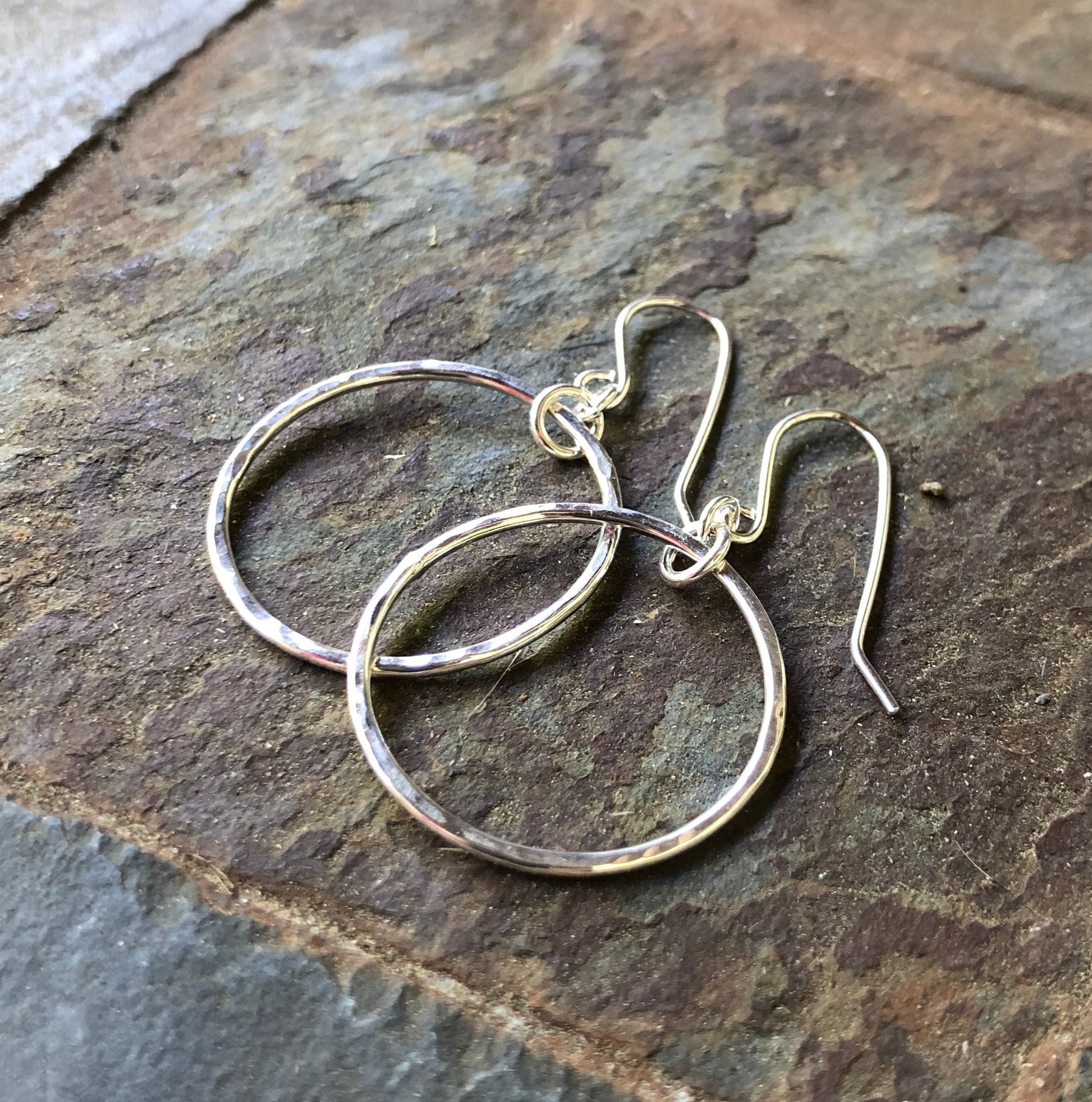 Silver hoop earrings on a stone surface