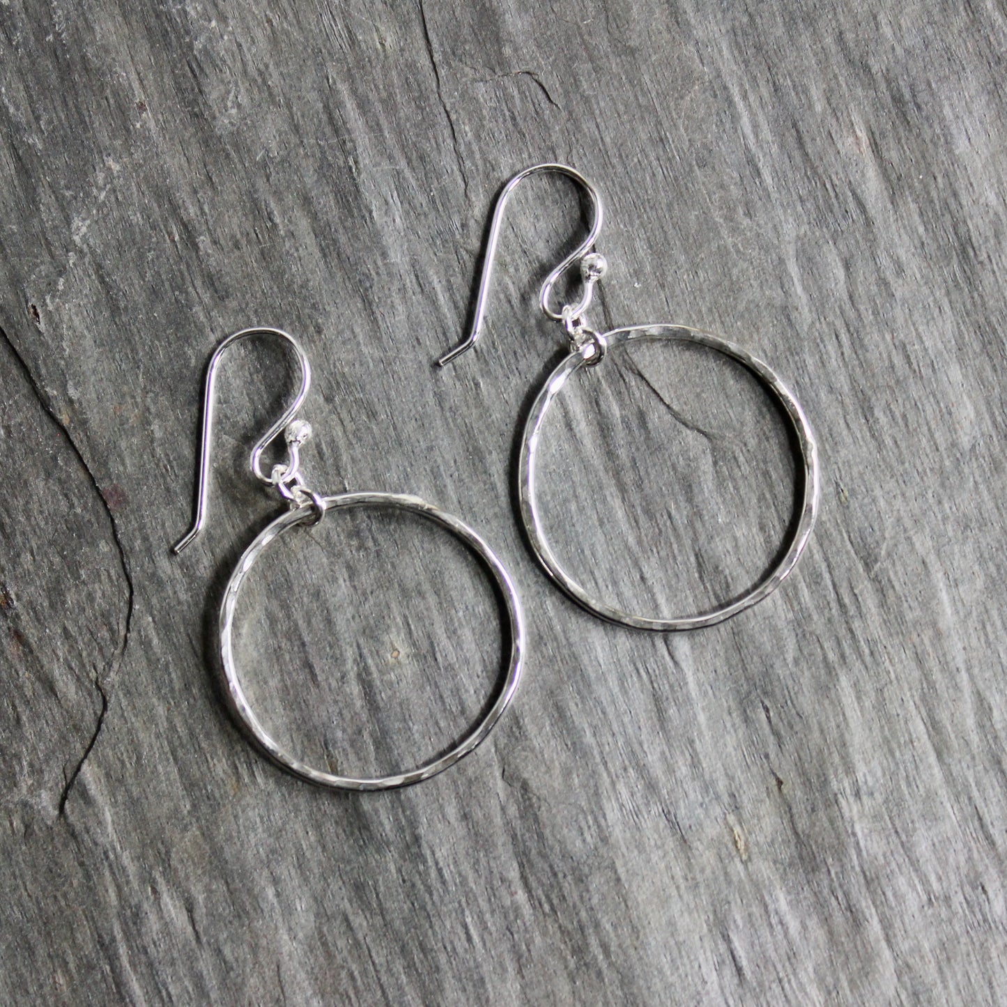 Pair of silver hoop earrings on a wooden surface
