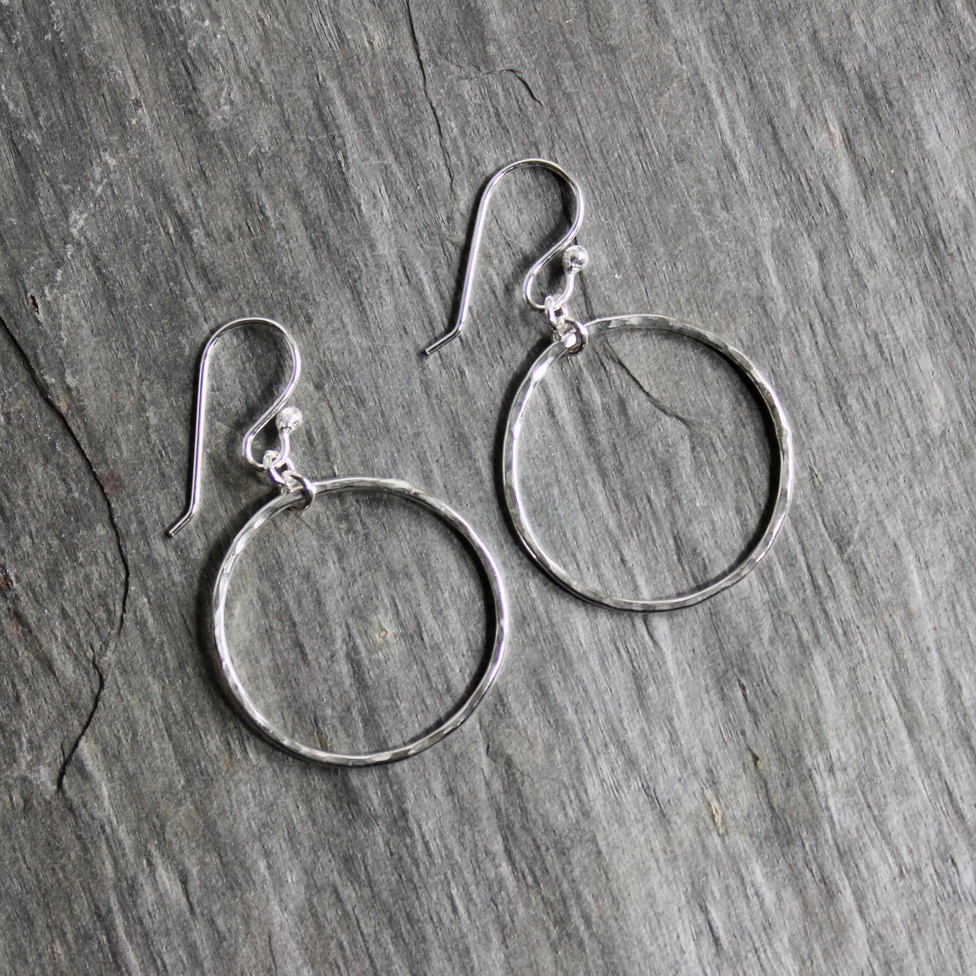 Pair of silver hoop earrings on a wooden surface